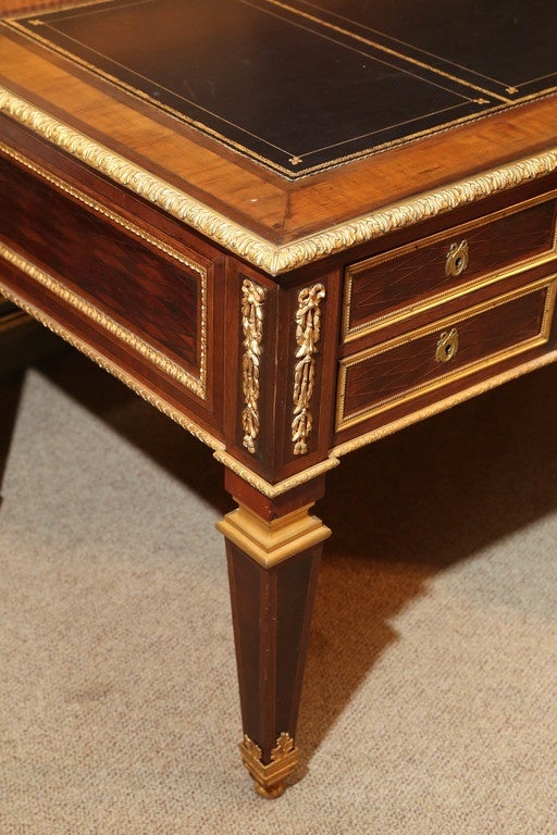 Rectangular top with an inset leather surface with bronze banding,
Above a case fitted with a single center drawer flanked by two
Additional drawers on either side, all with bronze dore appliqués ,
Raised on square tapering legs.