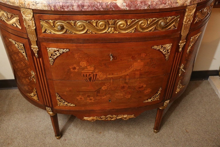 Early 20th century marble-top commode made with various exotic woods;
King wood, tulip wood and satinwood are combined to create intricate
Marquetry patterns. Floral and urn design decorate the front drawers
And a geometric pattern decorates the