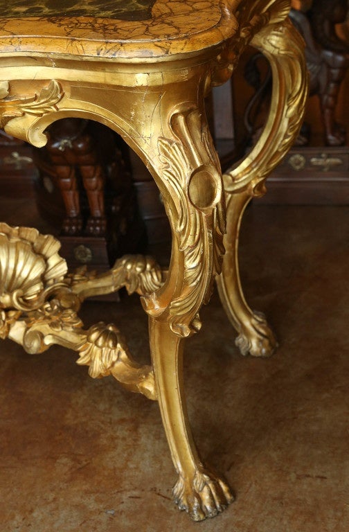Italian giltwood console in neoclassical design
Elegant curved leg ending in paw foot. Shell design 
Centers on  the stretcher and on the apron.
The top having a painted faux marble design in
Greens and gold colored paint.