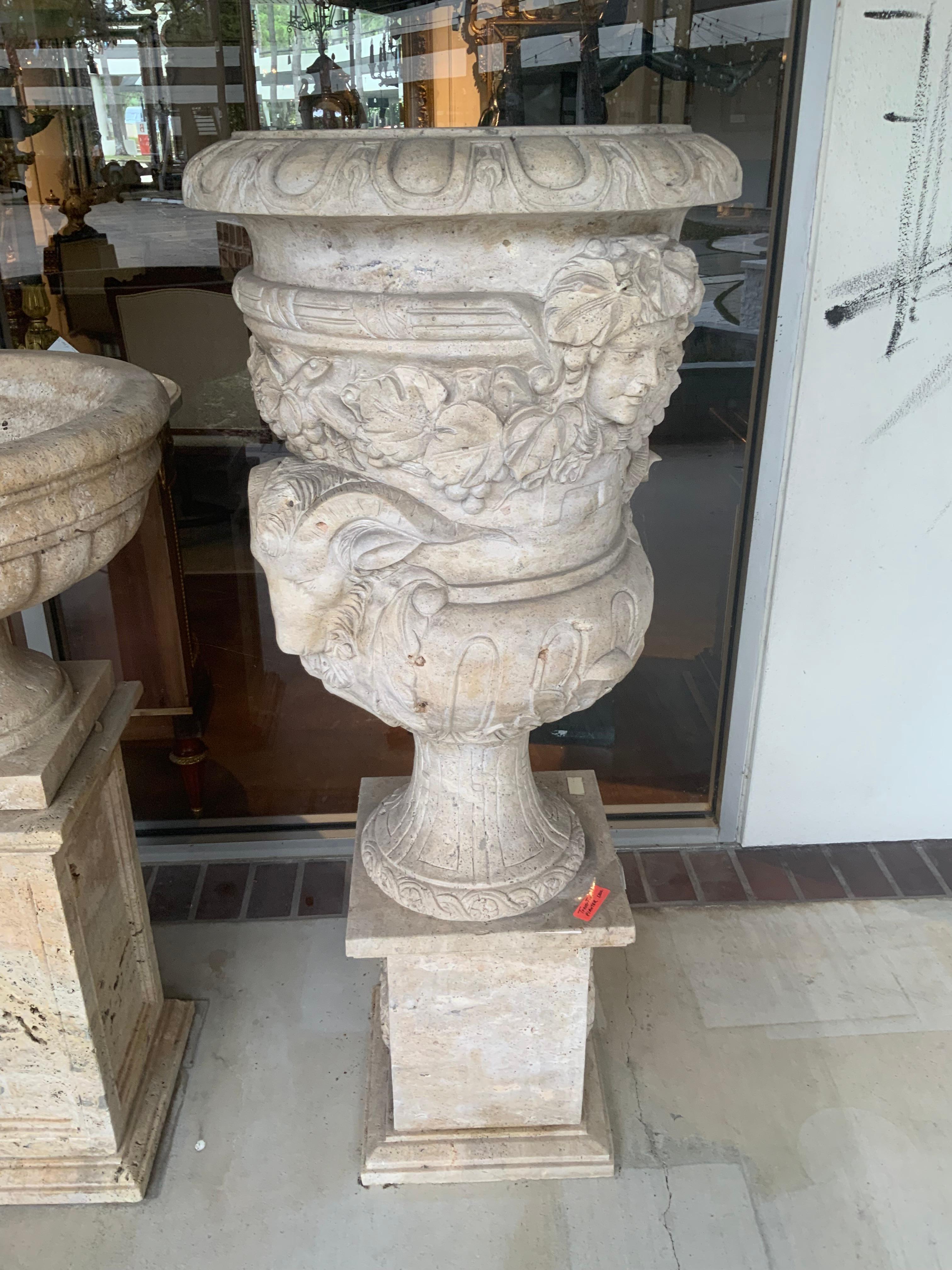 The depth of the carving is especially good on this large
Piece. It has rams heads carved on each side that
Are very special.  The planter sits on top of a square
Base for a special presentation. It is a travertine in
A pale gold hue and would