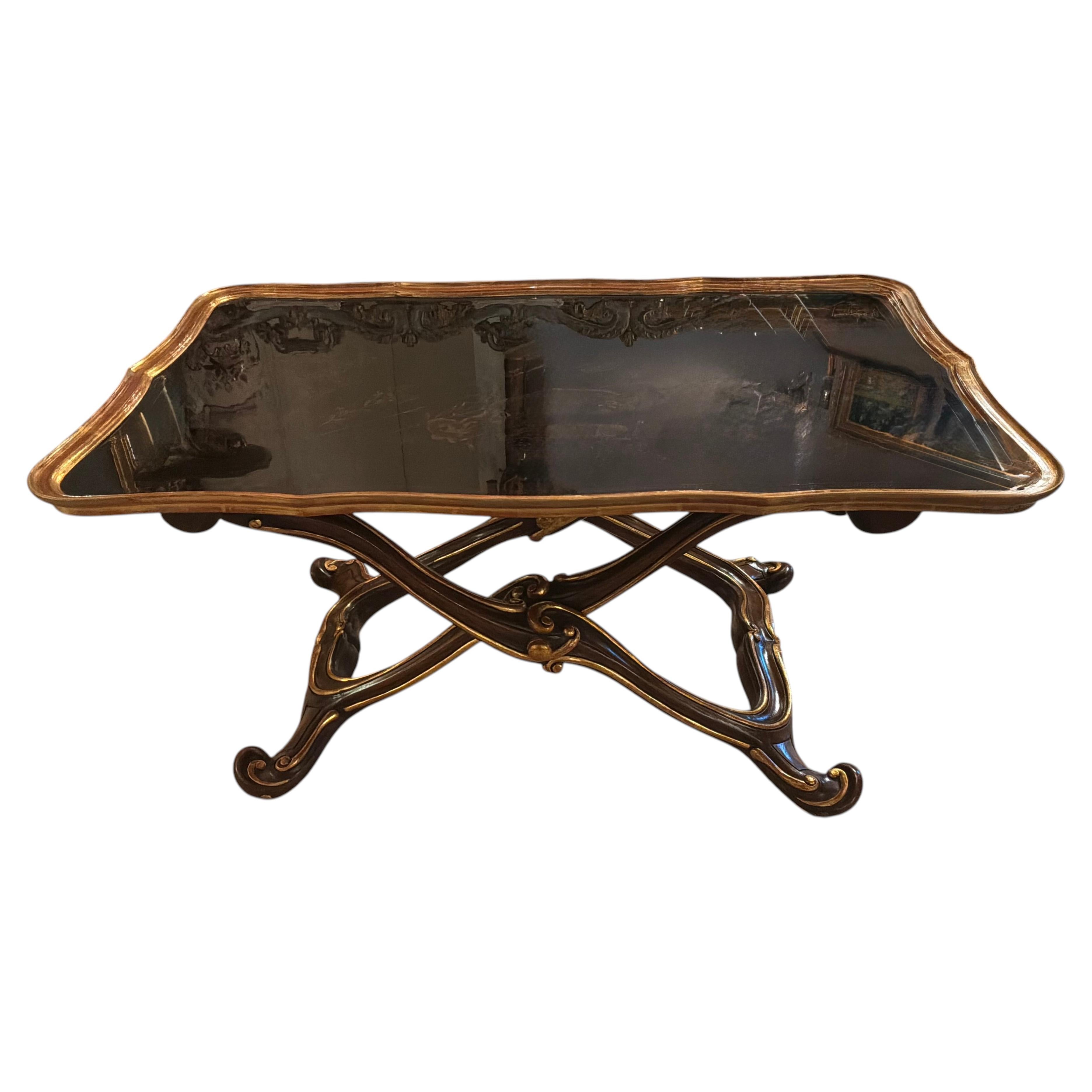 Tavolino nero e dorato con base a X e piano con motivi in stile chinoiserie