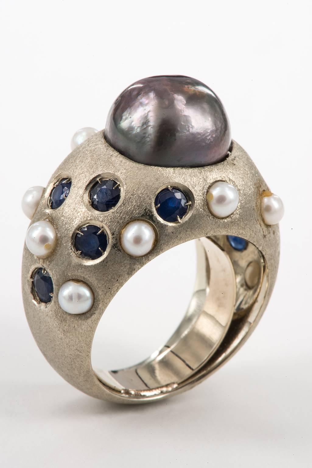 Unusual vintage ring in white brushed gold with Black Pearl from Tahiti diameter. 7 mm., with ten Sapphires and ten little Pearls.