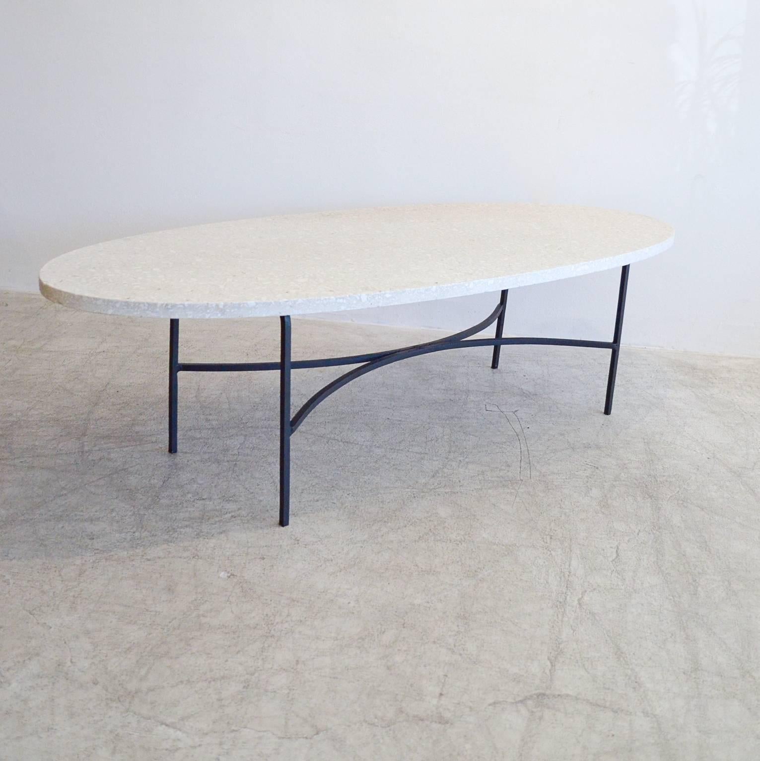 Elegant terrazzo and wrought iron coffee table in the manner of Harvey Probber. Beautiful ivory terrazzo with black iron frame base in excellent condition. 

Rare oval size, very elegant piece for your home.

Measures: 60