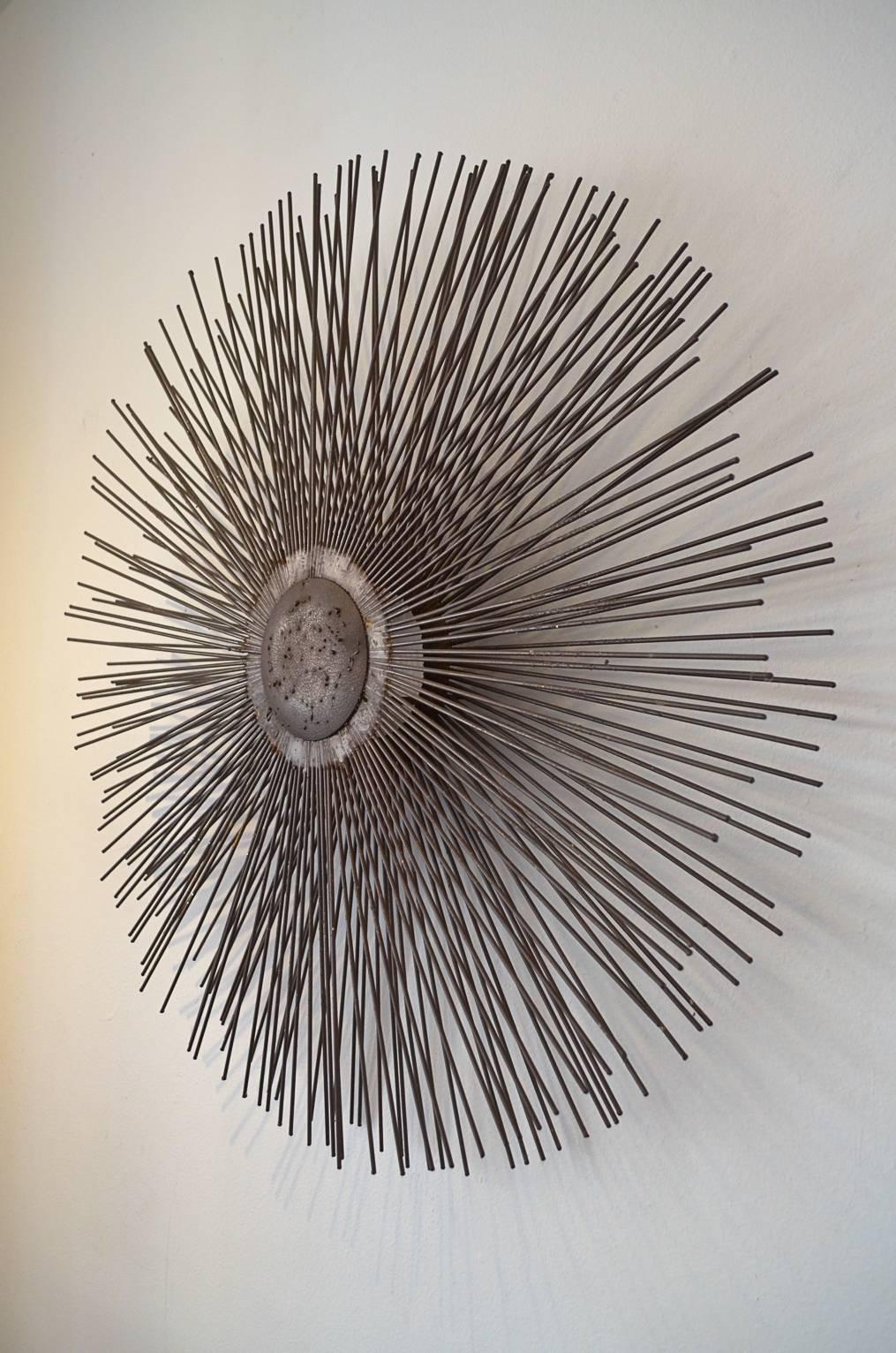 Metal sunburst wall art or sculpture in the manner of Curtis Jere. Three dimensional piece, contains two rows of spokes and sits 4
