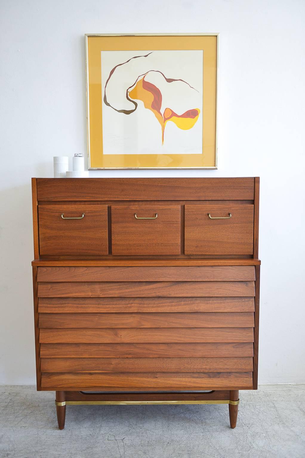 Walnut and brass highboy dresser or gentlemen's chest by Merton Gershun for American of Martinsville. Original brass hardware detail. Professionally restored in showroom condition. Offers lots of storage options for smaller spaces.

Measures: 38