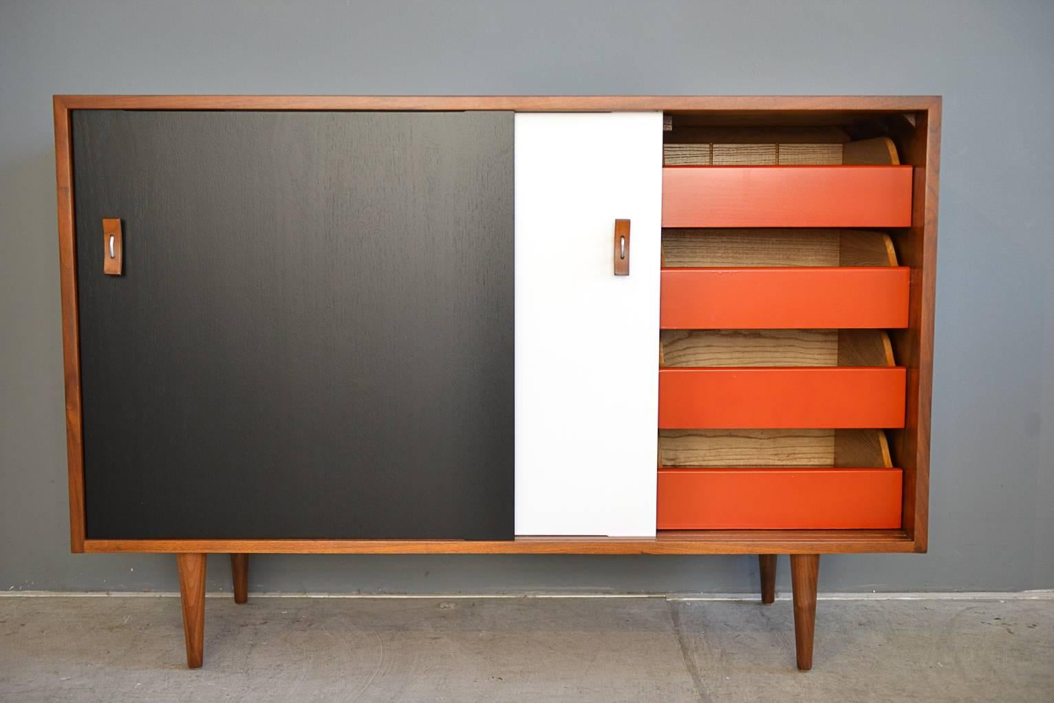 A new twist on a classic, this beautiful petite credenza has been professionally restored and updated with black and white sliding doors. Hardware is original as well as the red drawers behind the cabinet.

Showroom condition.

Measures: 48