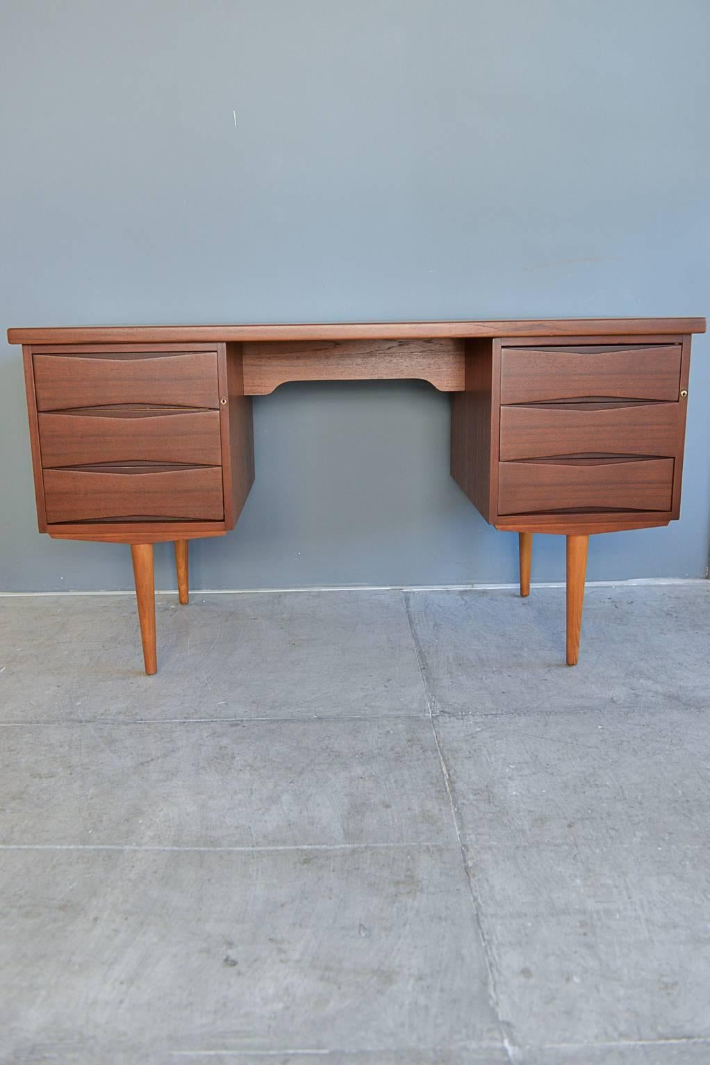 Sleek and beautiful teak bowtie front desk by Skeie Norway. Professionally restored with sculpted legs and beautiful bowtie front drawer pulls. Left drawer has hanging file folder brackets and right side has three drawers that are open.

Perfect