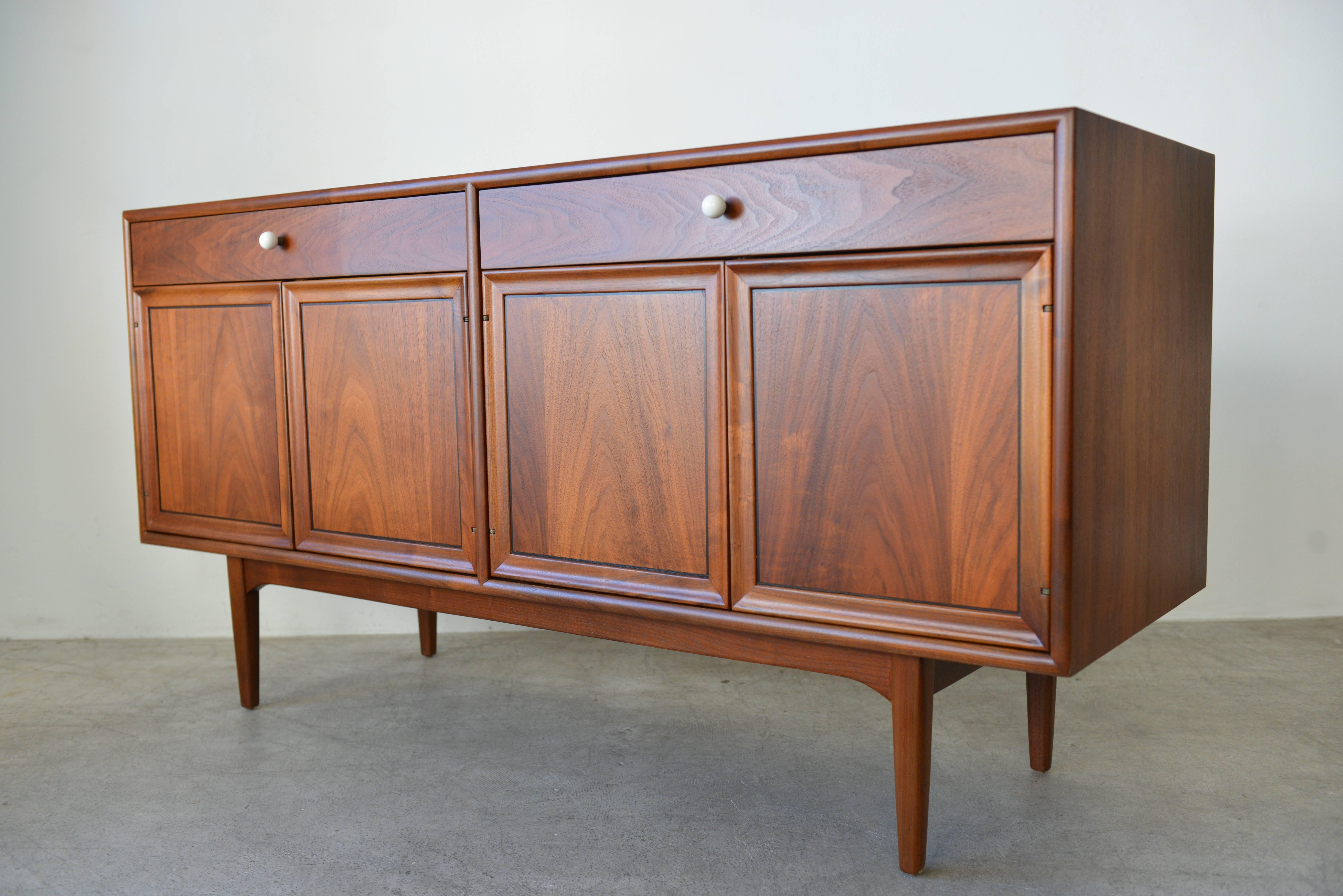 This Kipp Stewart walnut credenza by Drexel Declaration. Beautiful bookend matched doors with original porcelain pulls. Interior lights come on with the doors open. Shelves are adjustable.

Condition is excellent, restored to showroom