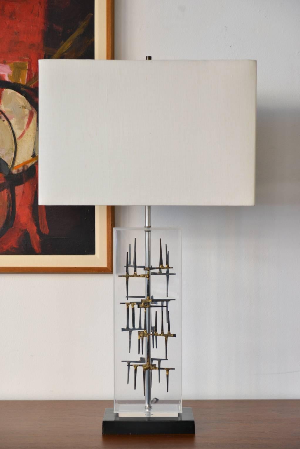 Lucite and Brutalist sculptural lamp by Laurel Lamp Company, circa 1970. Beautiful clear Lucite with nail head design with just the right amount of patina. Metal base in excellent condition with original wiring.

Includes square linen shade.