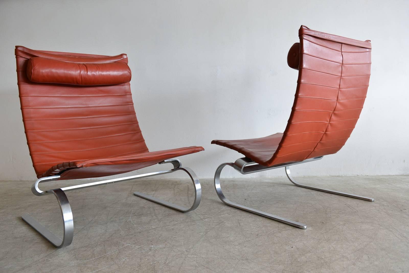 Beautiful pair of brick leather PK-20 lounge chairs by Poul Kjærholm for Fritz Hansen, circa 1989. Original brick or cognac colored leather with original neck bolsters. Marked on underside. Sculpted steel frame in excellent condition with no rust or