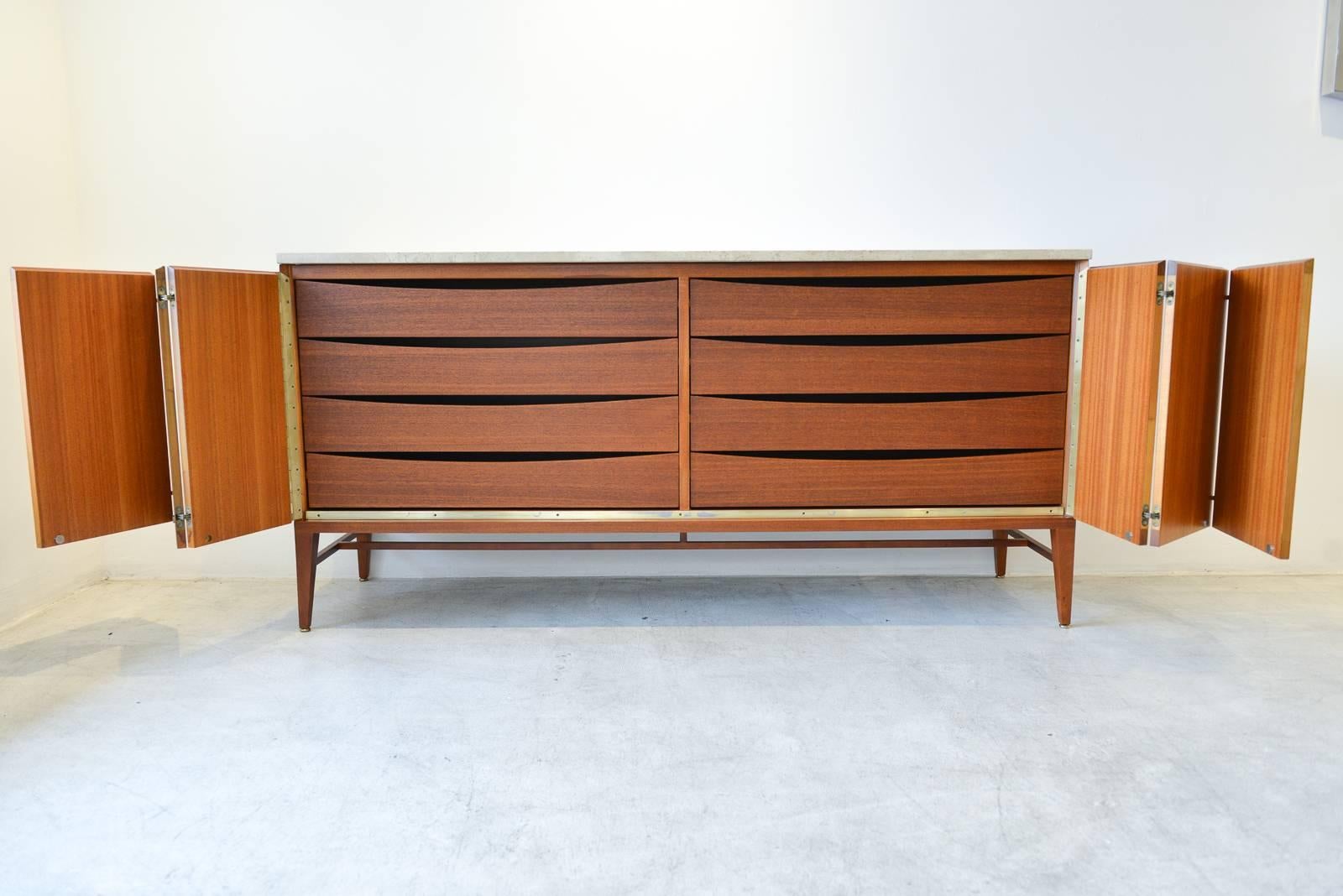 Paul McCobb for Calvin Group mahogany and travertine credenza or sideboard. Finished on back, can float in a room. Tons of storage with eight interior drawers, accordion front doors and original brass hardware.

Professionally restored in showroom