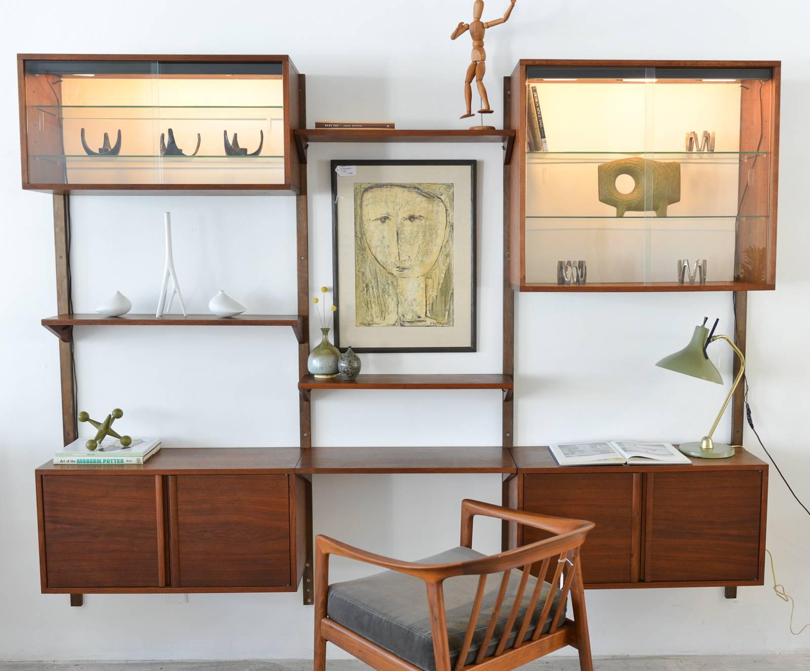 Walnut 3 bay wall unit with lighted cabinets, circa 1970. Includes two additional shelves, not shown in photos and all mounting hardware. 

Walnut is in very good to excellent condition and glass is perfect. Original lighting and wiring. Lower