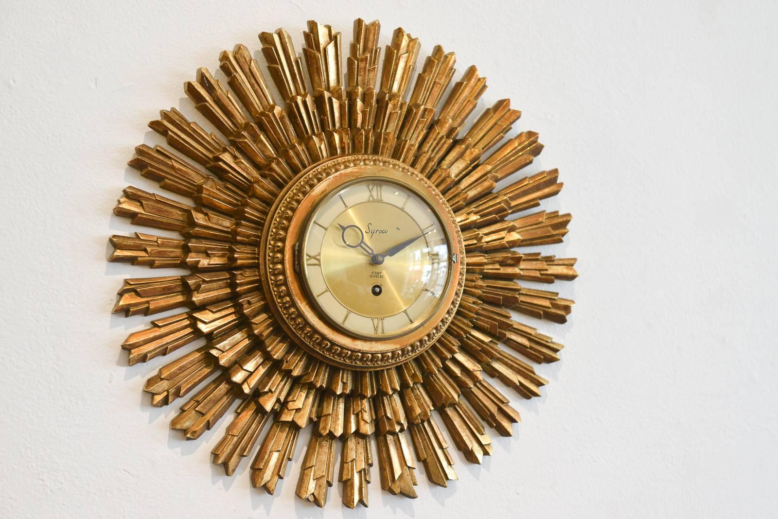 Gold gilt sunburst clock by Syroco Wood of Syracuse, NY, circa 1955 with original key wind mechanism, hour and minute hands and domed glass cover. 8 day jeweled movement.

Excellent vintage condition, works perfectly keeps excellent time. Does not