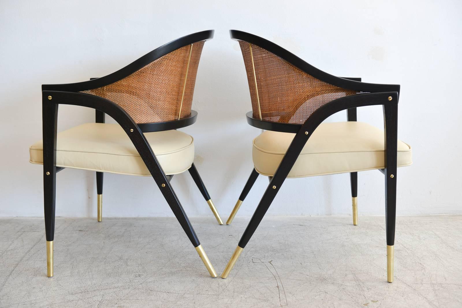Edward Wormley for Dunbar Style 5480 pair of sculpted armchairs, circa 1955. Fully restored, ebonized frames with new ivory leather upholstery and new cane backs. Beautiful brass detailing. Rare, hard to find sold as a pair only. Showroom