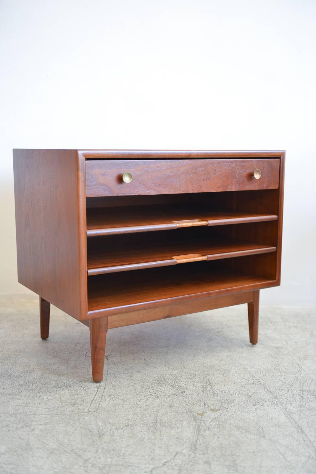 Kipp Stewart walnut nightstand or end table with pull out magazine shelves, circa 1965. Beautifully restored walnut with cane wrapped pull out shelves. Showroom condition.

Measures 26