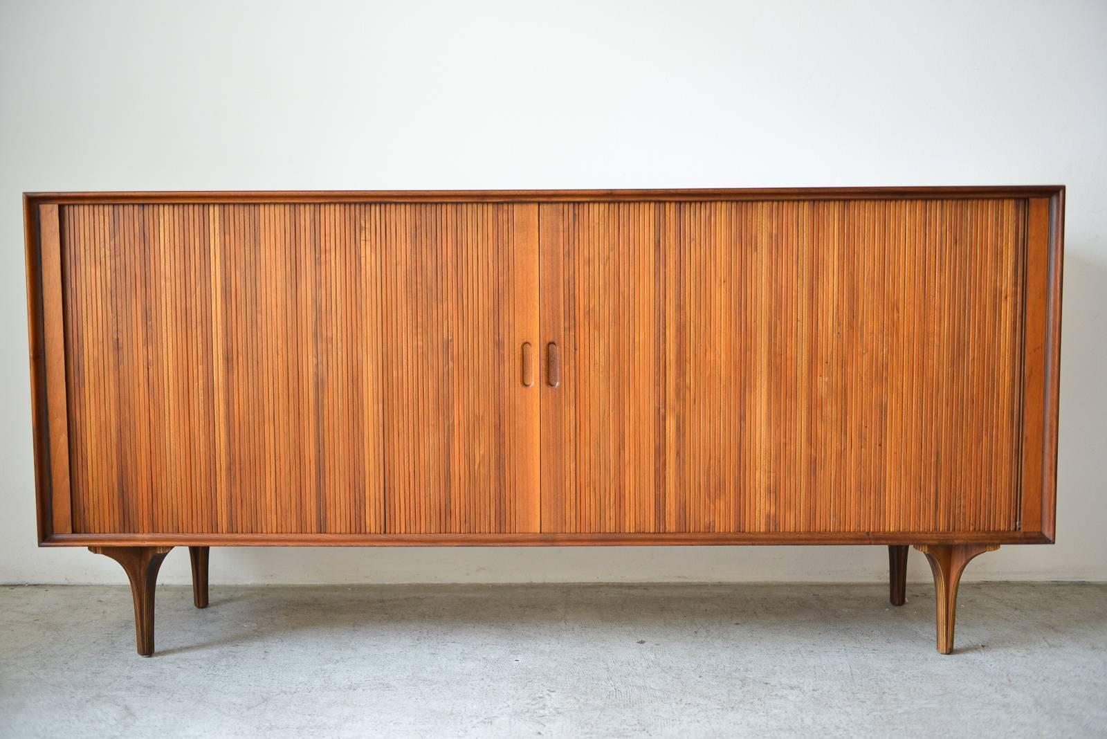 Walnut tambour door credenza by Robert Baron for Glenn of California, circa 1965. Beautiful walnut sliding tambour doors and inner adjustable shelving with vertical slots for records or media. Wood has been professionally restored and piece is in