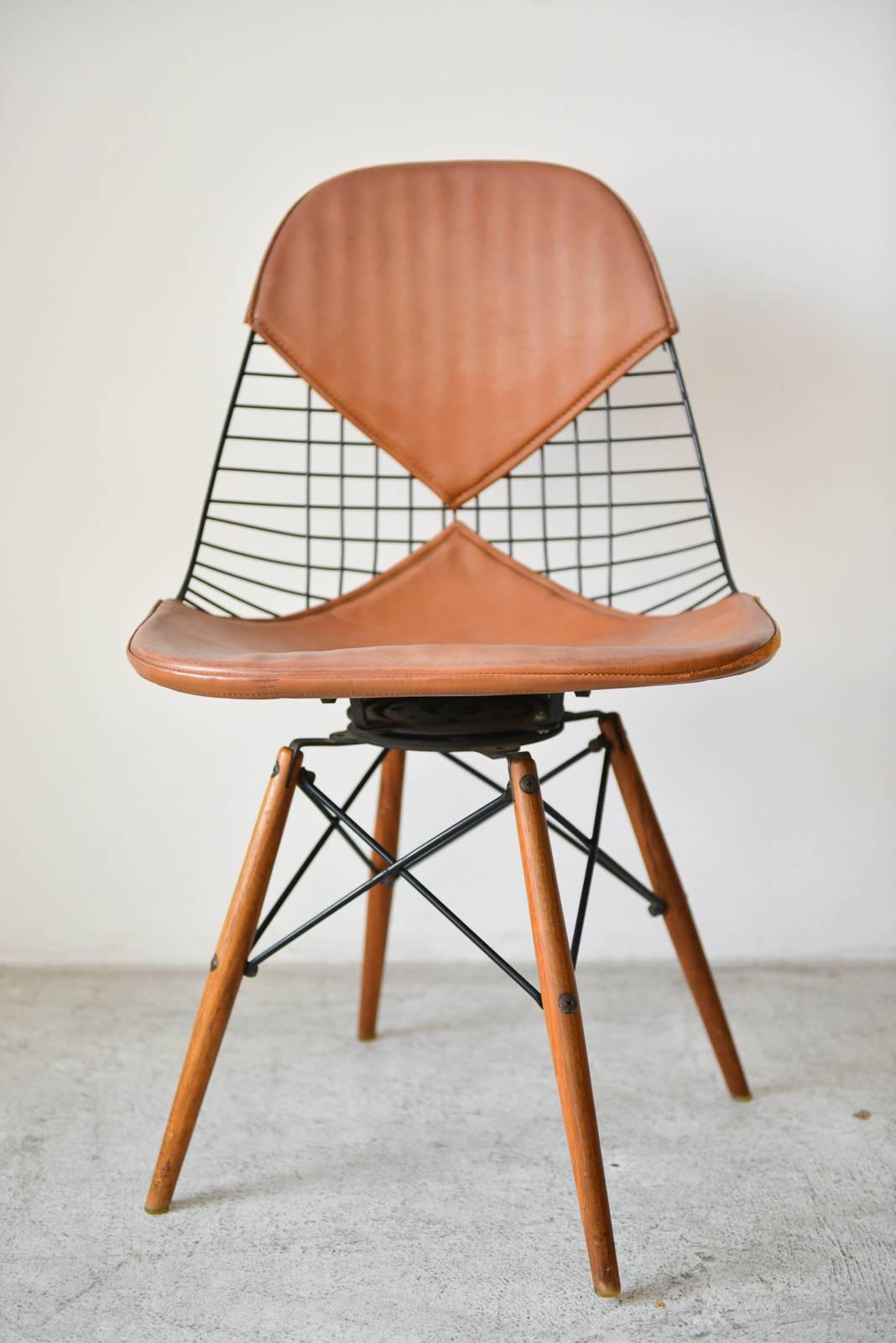 First generation Eames PKW-2 wire chair with walnut dowel legs, circa 1951. Brown saddle leather bikini cover and swivel base. Highly collectible, this particular chair has the walnut dowel legs with swivel base and beautiful patina on the saddle