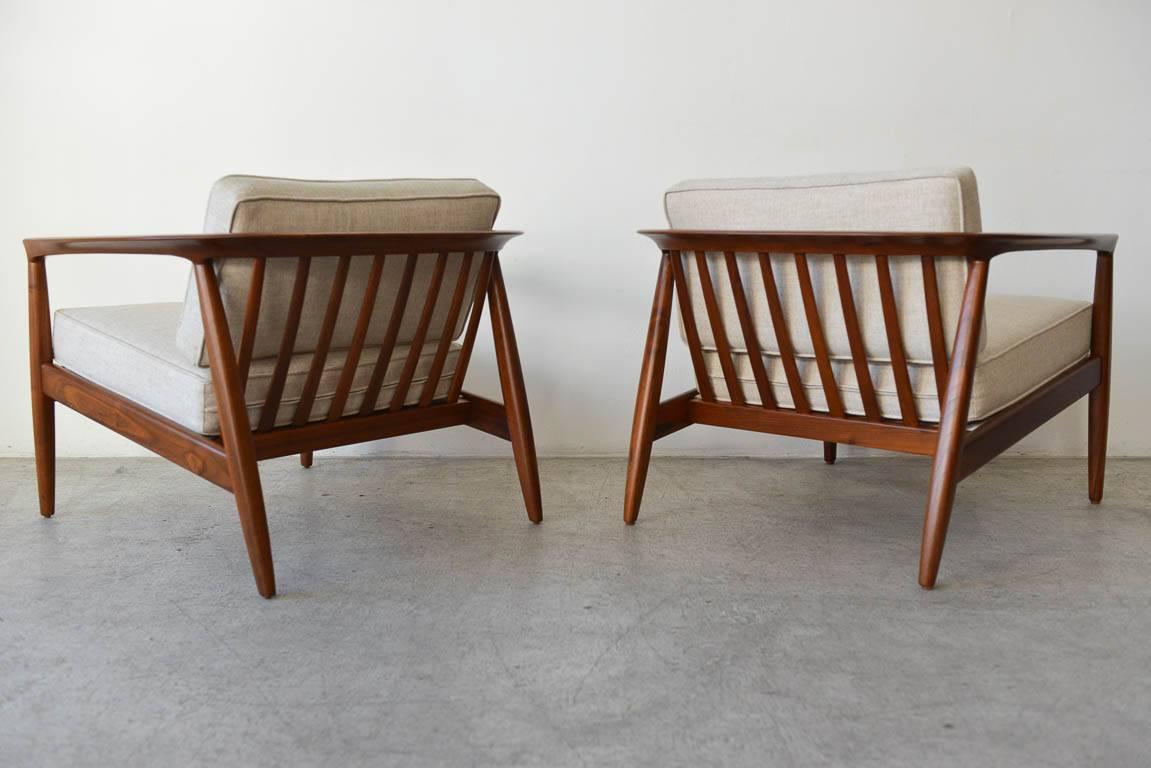 Pair of Folke Ohlsson for Dux barrel back lounge chairs. Professionally restored in showroom condition with new linen upholstery and new foam. Walnut wood frames and finished under seat make these highly desirable pieces.

Measures: 30