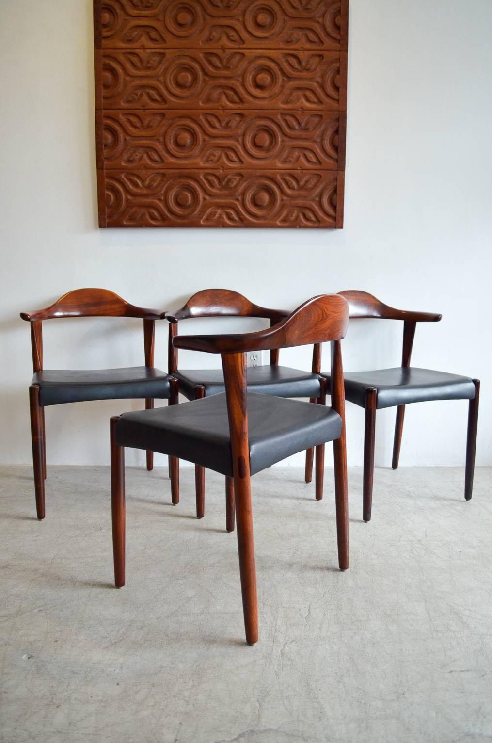 An exceptionally crafted Danish rosewood dining set by Harry Ostergaard for Randers Mobelfabrik. Hand-sculpted chairs resemble Han's Wegner's bull horn chair. These are done with solid rosewood with excellent leg detail and inserts with curved backs