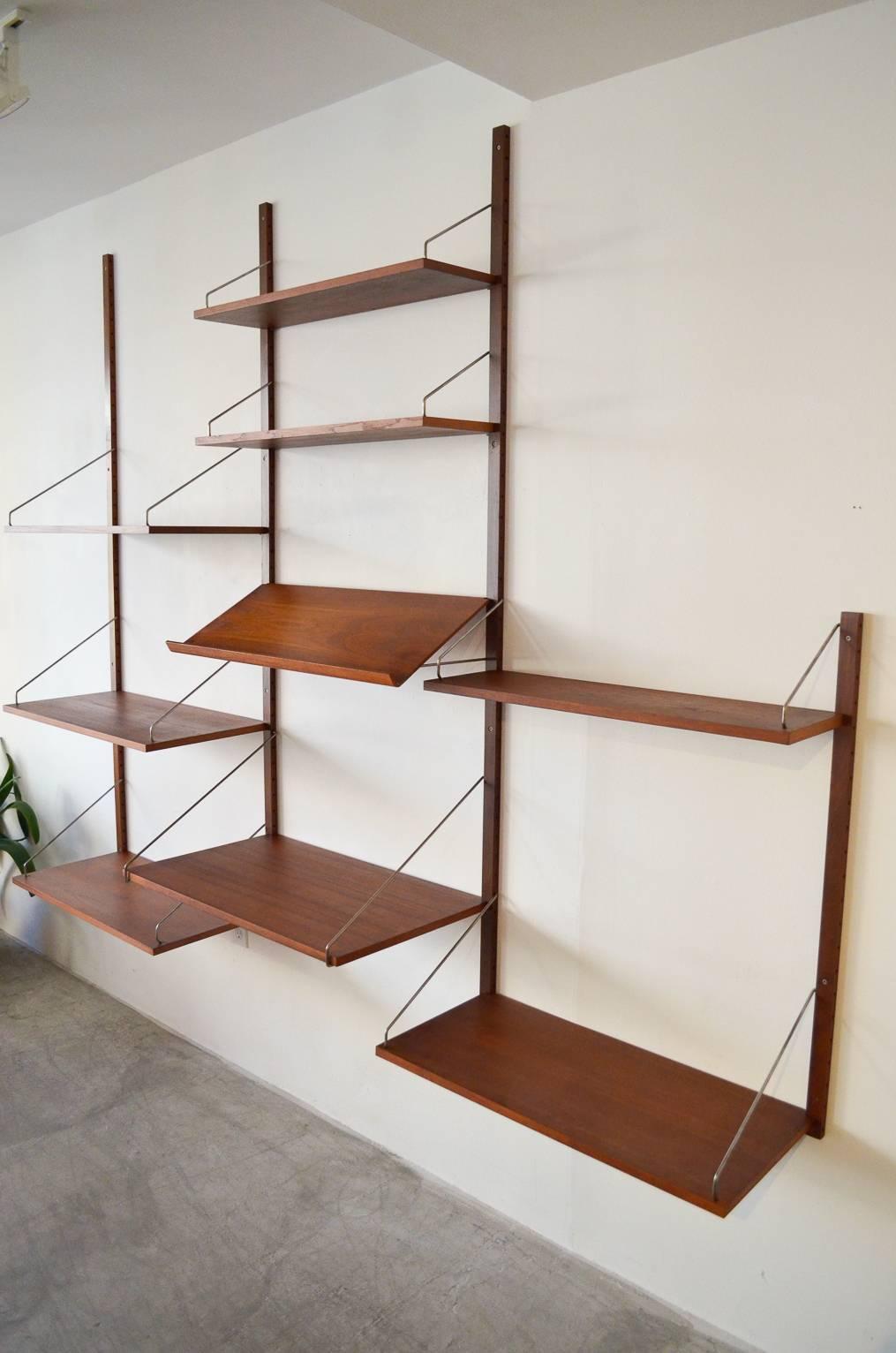 Fully customizable teak shelving or wall unit by Poul Cadovius. Commonly called 'Cado,' designed by Poul Cadovius of Denmark. Very good condition includes all hardware.

Wall-mounted unit includes nine shelves and a hard to find magazine rack and