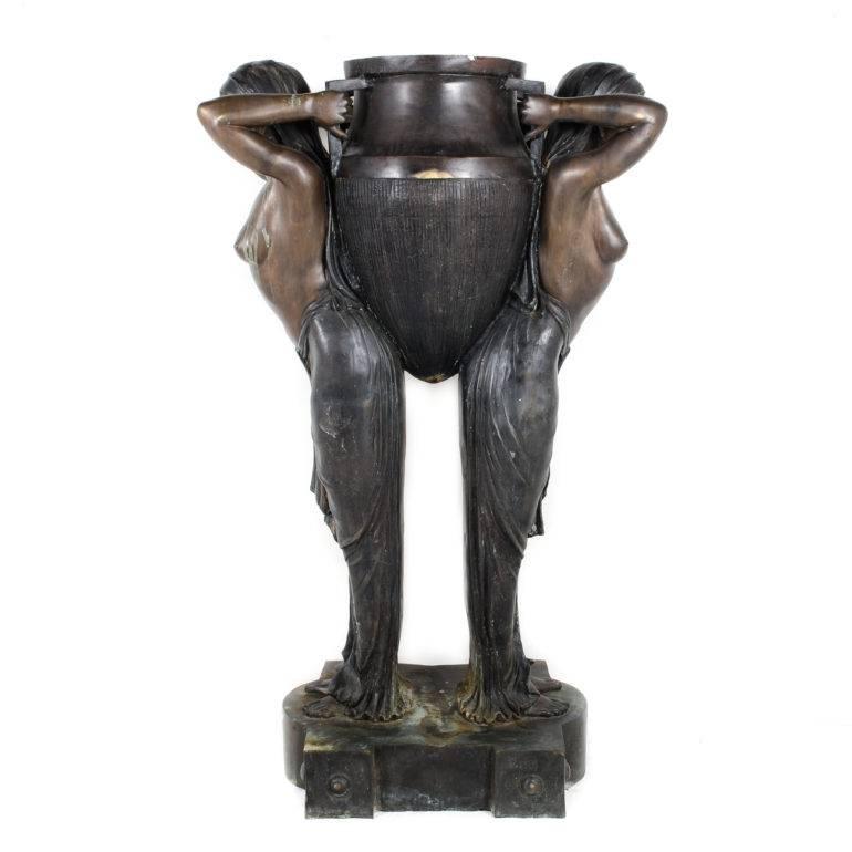 Monumental sized, standing 5'7″ tall, this highly decorative bronze Art Deco style statue of two identical women holding an urn is from the late 20th century with its original patina.
                                 