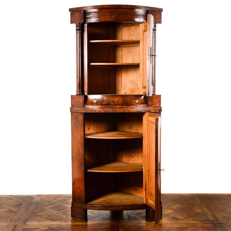 Antique mahogany Biedermeier-style corner cabinet, having upper and lower cupboards, each with shelves, and a single drawer between. Original hardware and keys. Most likely German. Circa 1840.
 