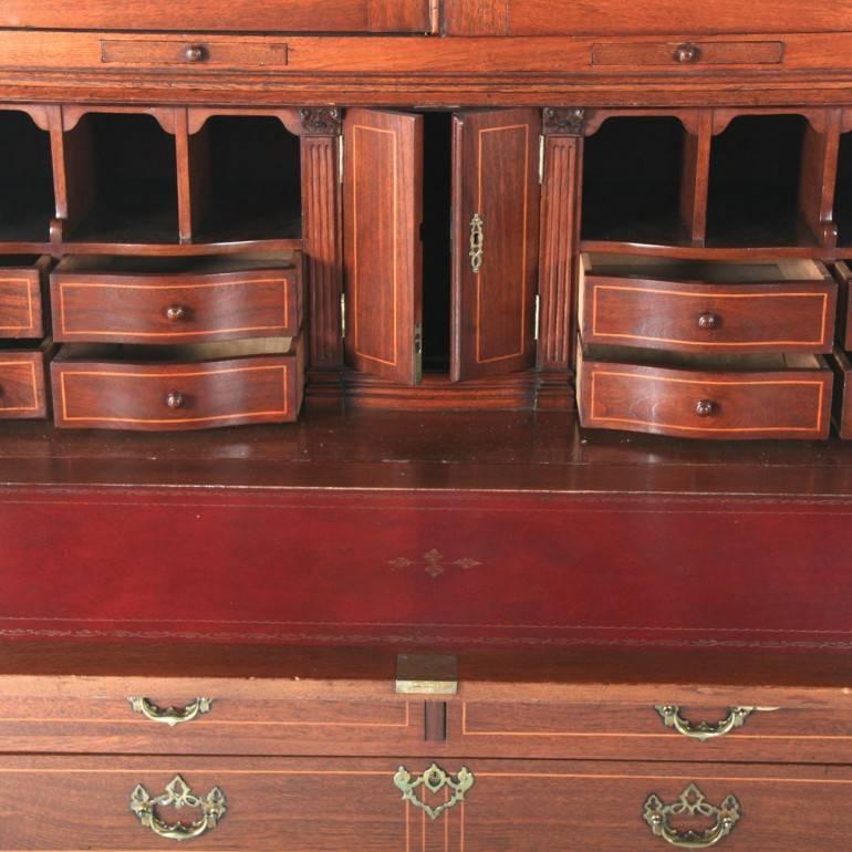 A grand, 19th century, antique bureau bookcase in solid teak, inlaid with boxwood and with an ornately-fitted upper section. Beautifully detailed with original pulls and inlay, this impressive bureau bookcase stands over 8′ tall.



  