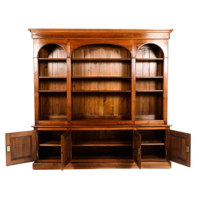 A large, vintage French bookcase. Solid cherry with three arched, open upper sections over four lower enclosed sections. Circa 1950. In excellent condition.



