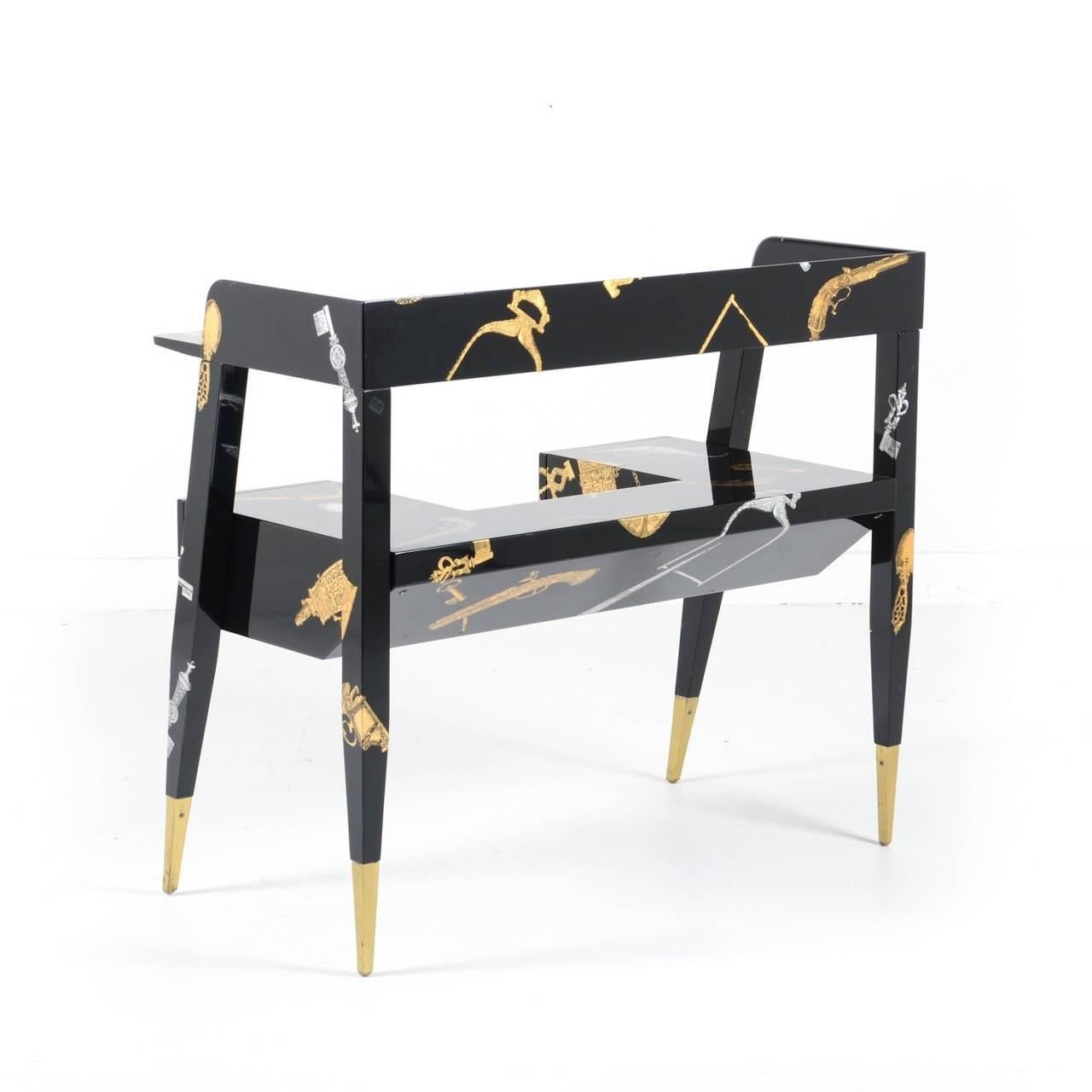 'Chiavi et Pistole' desk designed by Gio Ponti (1891-1979) and Piero Fornasetti (1913-1988). A stunning black lacquer four-drawer desk on brass sabots. Printed with pistol and key motif in silver and gold. Marked 