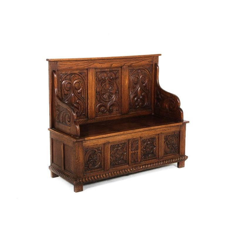 Highly carved English oak hall bench, circa 1895, with profusely-carved arms and raised panels to back and front. Storage under seat.  In excellent original condition. 





 