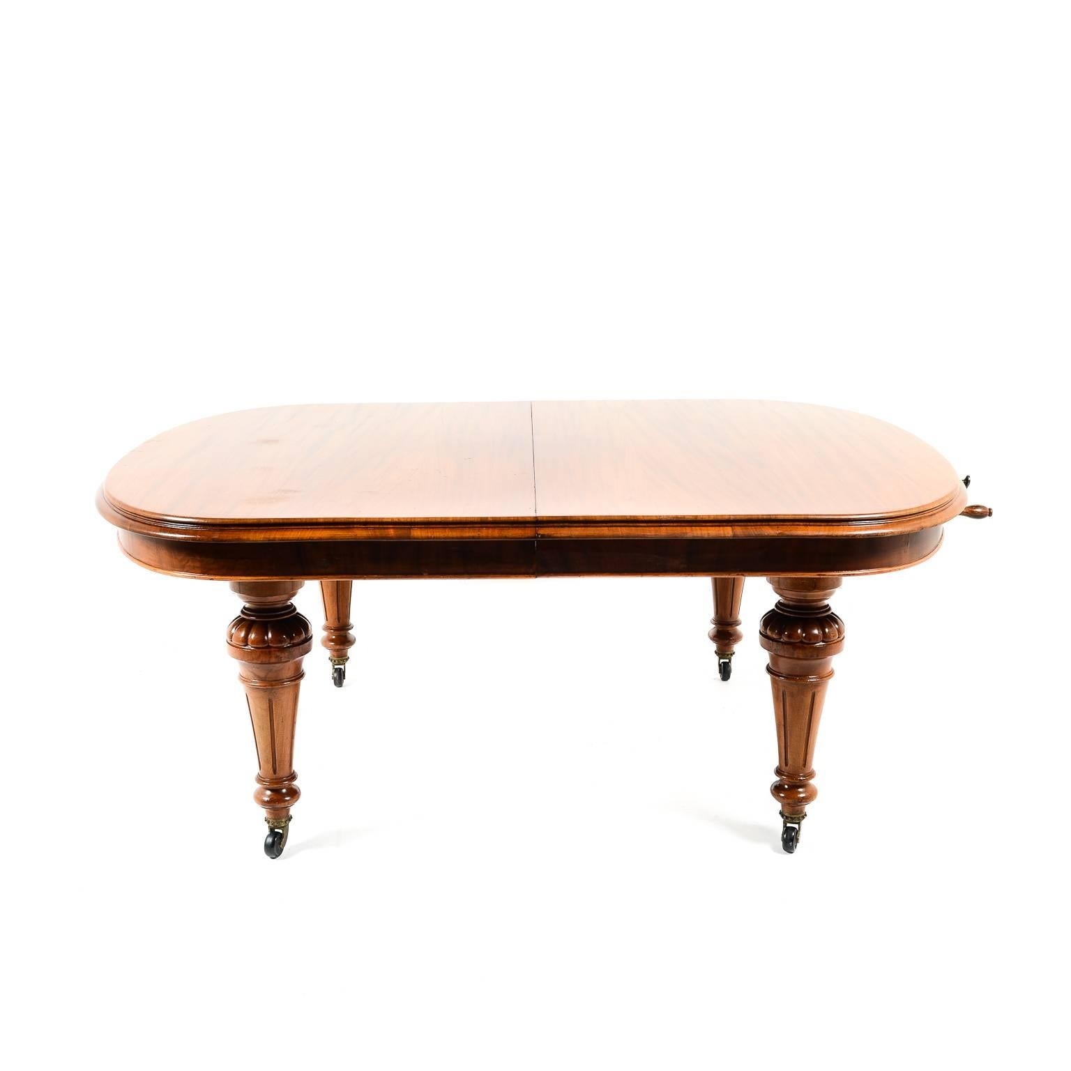 Antique English solid mahogany extending dining table with two leafs. Brass crank-handle used to extend and contract the piece, circa 1880. Beautiful finish and sturdy, finely-carved legs.





