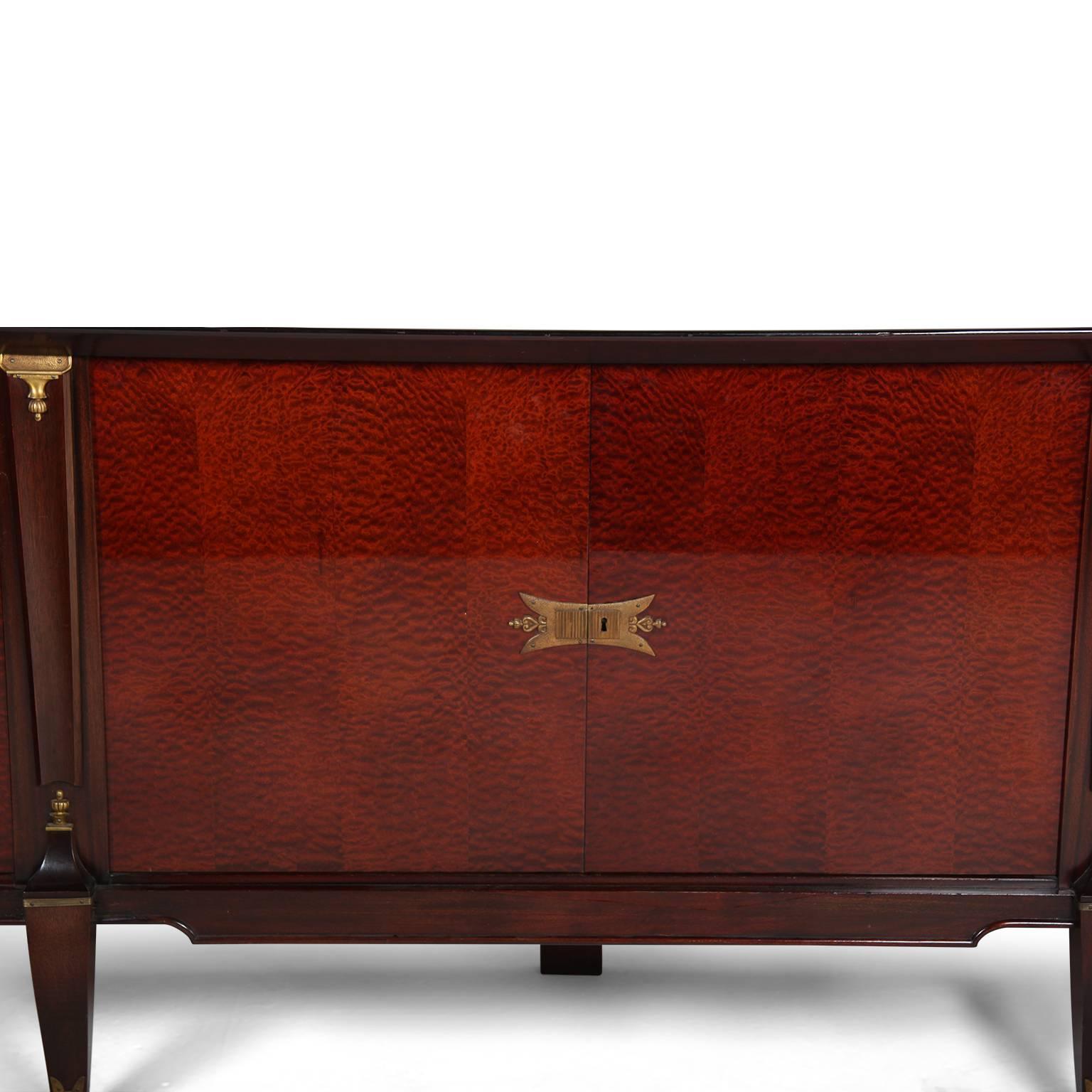 A French Mid-Century side board in mahogany with brass mounts a long, but well-proportioned, piece with a deep lacquered finish, dramatically-figured veneer on the doors and a beautiful mahogany color, circa 1950.



  