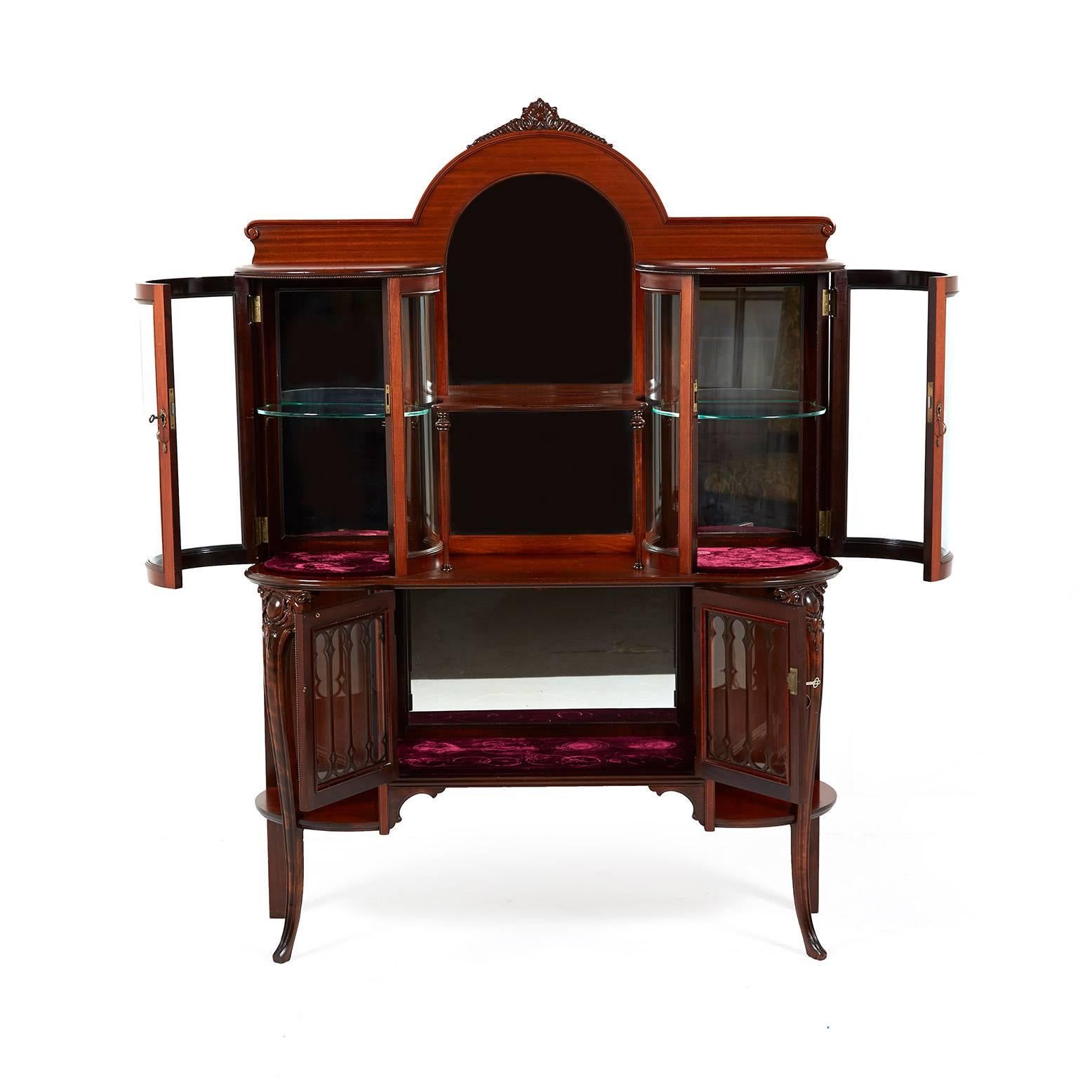 Antique American Victorian china cabinet with unusual curved glass display, circa 1890. This is an American production in the Classic Victorian style. Very solid mahogany with impressive curved glass display portion. Delicate wooden fretting on the