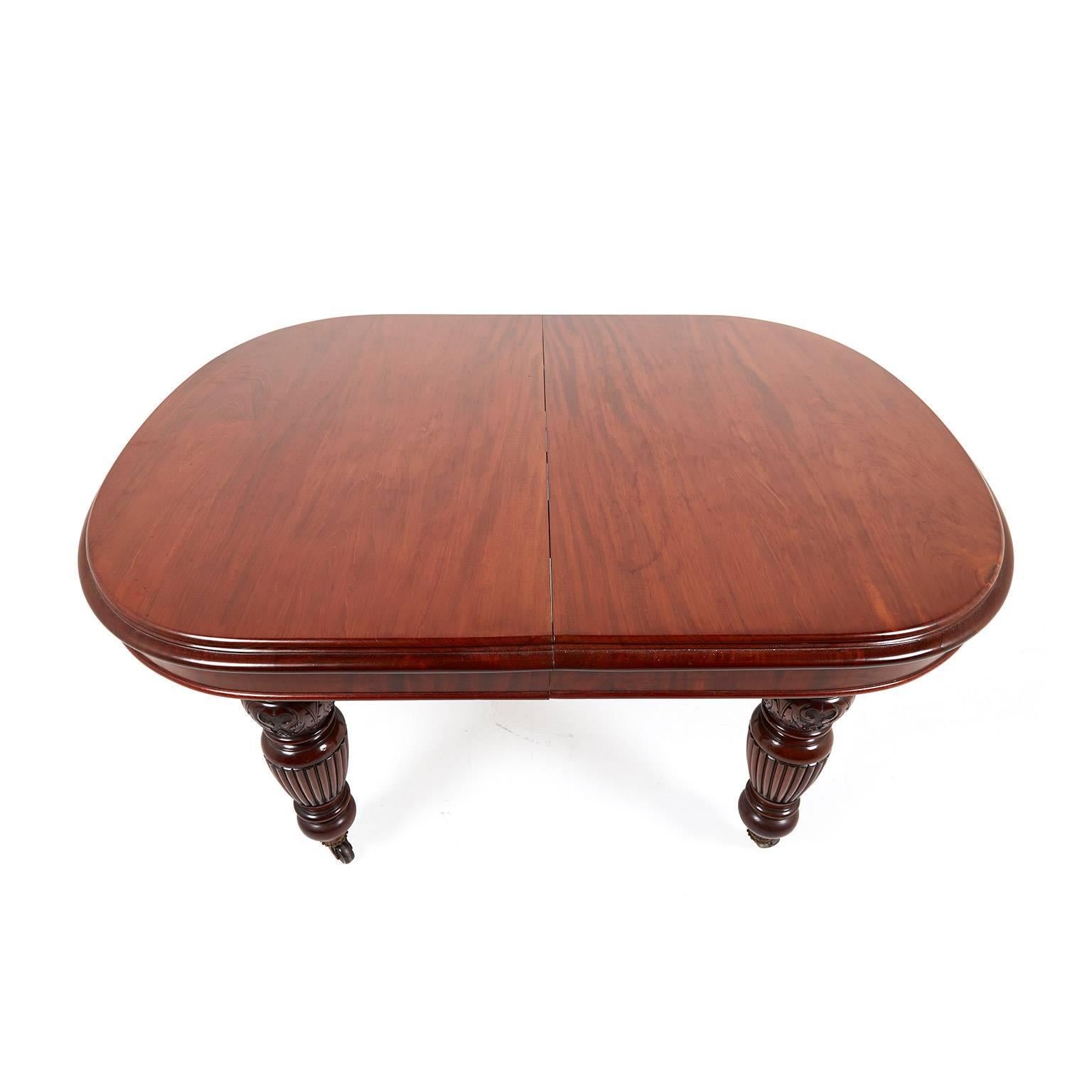 English mahogany Victorian dining table with two leaves, circa 1870. Hand-crank operation for inserting leaves. Really outstanding condition on this piece. With solid carved legs, this table is suitable for everyday use. Original casters. 

Each