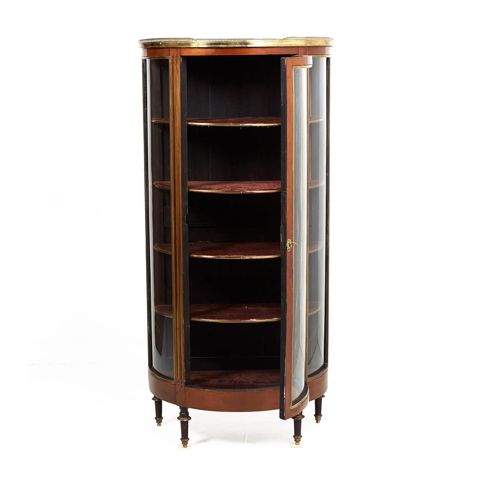 Antique Napoleon III mahogany demilune vitrine with brass trim, topped with contrasting light-coloured marble that’s surrounded by a delicate brass gallery. Versatile size makes it ideal for many different locations in your home, circa