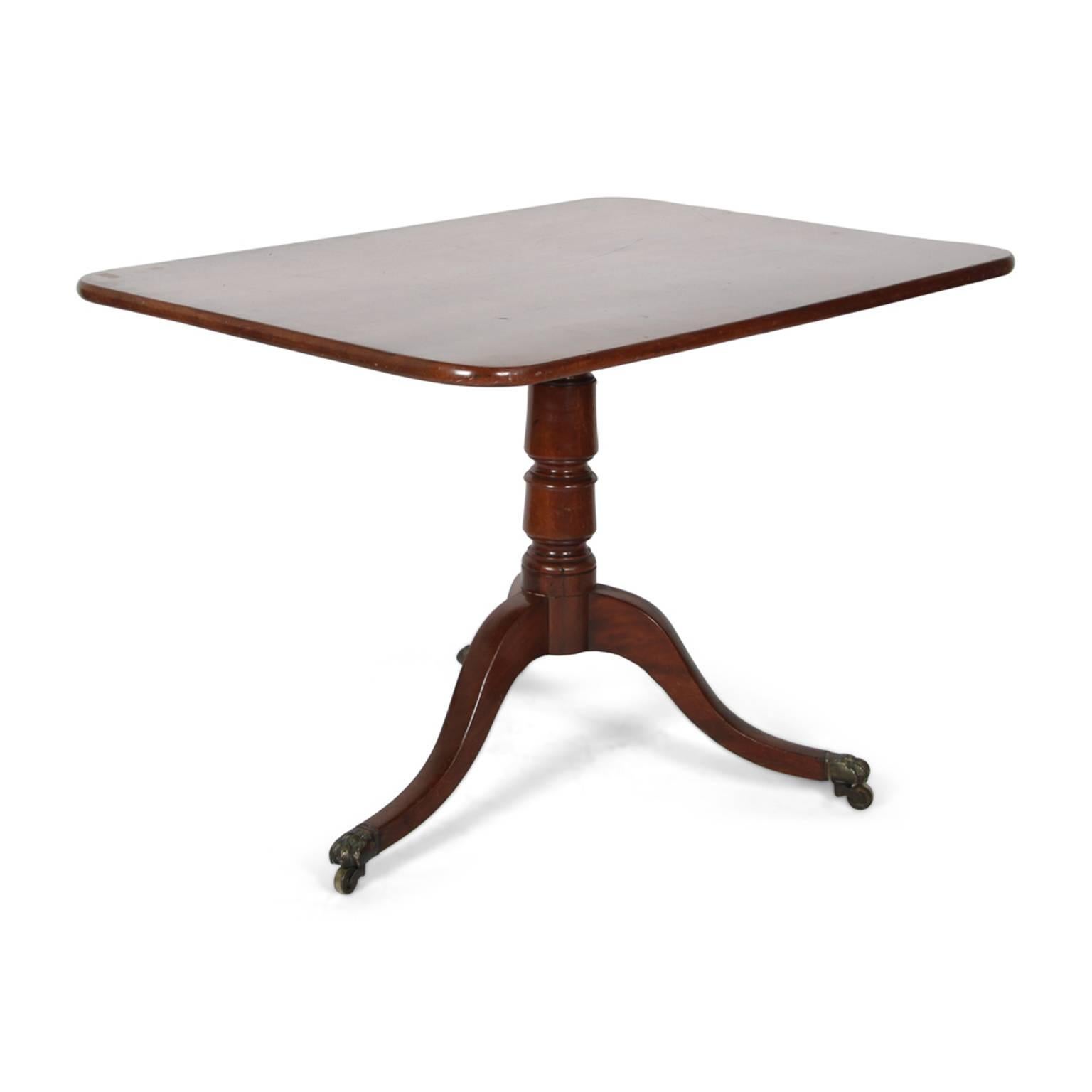 An English Georgian ’tilt-top’ breakfast or side table, the top a single board of mahogany, with a pedestal base on three legs, with brass castors, circa 1825.



        