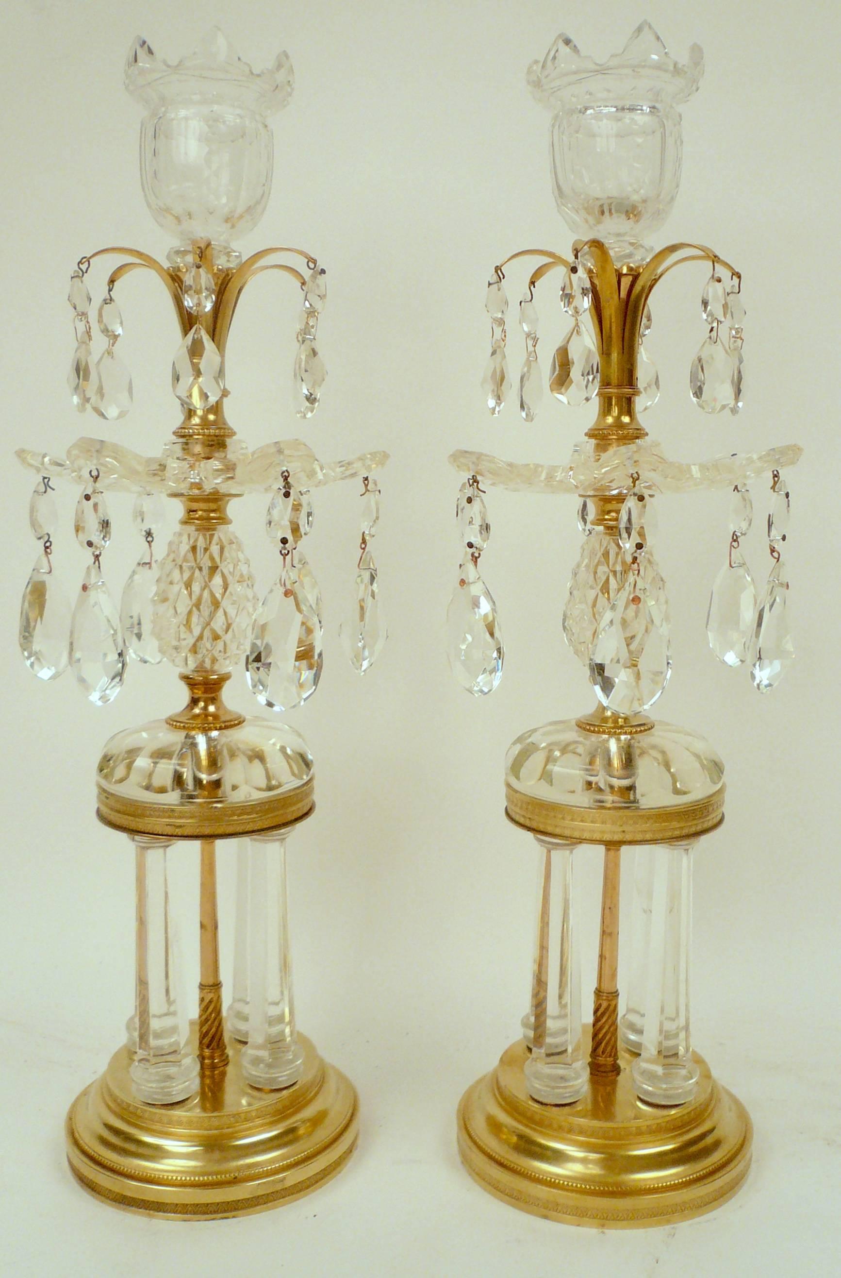 A fine pair of late 18th century cut crystal temple form candlesticks attributed to Parker and Perry with Vandyke bobeches and candle cups, and cut-glass drops.
The bronze stepped plinth form bases with cut crystal columns support a faceted crystal