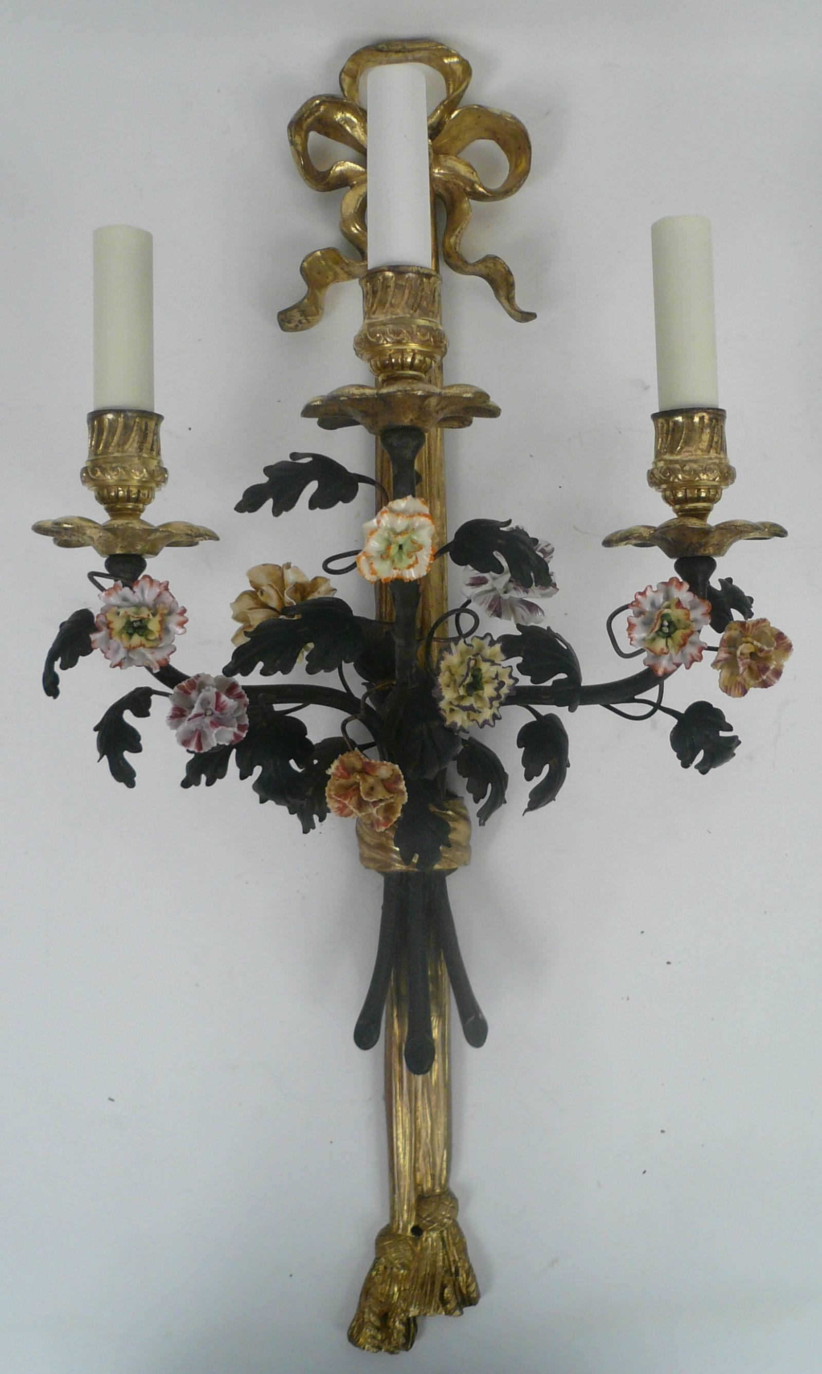 This beautiful pair of bowknot, ribbon and tassel form sconces feature enameled leaves and hand-painted porcelain flowers. They have been rewired and are ready for use.