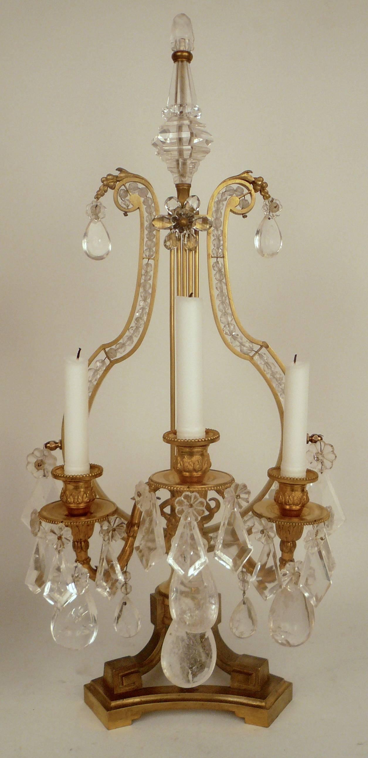 This pair of French girandoles or lustres, feature neoclassical motifs, including ram's heads and lyre form backs.