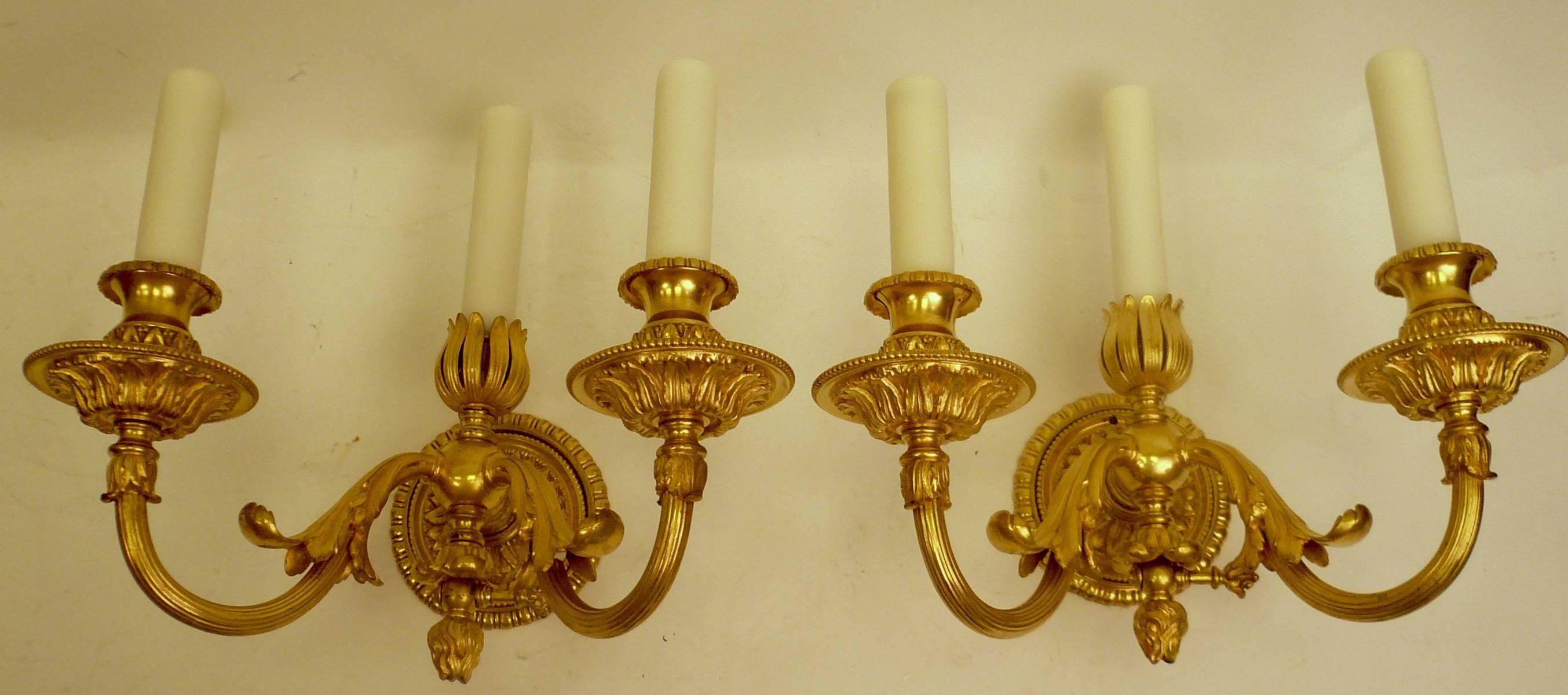 This pair of sconces originally gas powered, have been wired for electricity. They feature hand chased Classical motifs including acanthus leaves and flame finials. They are finely detailed, and retain their original gilding.