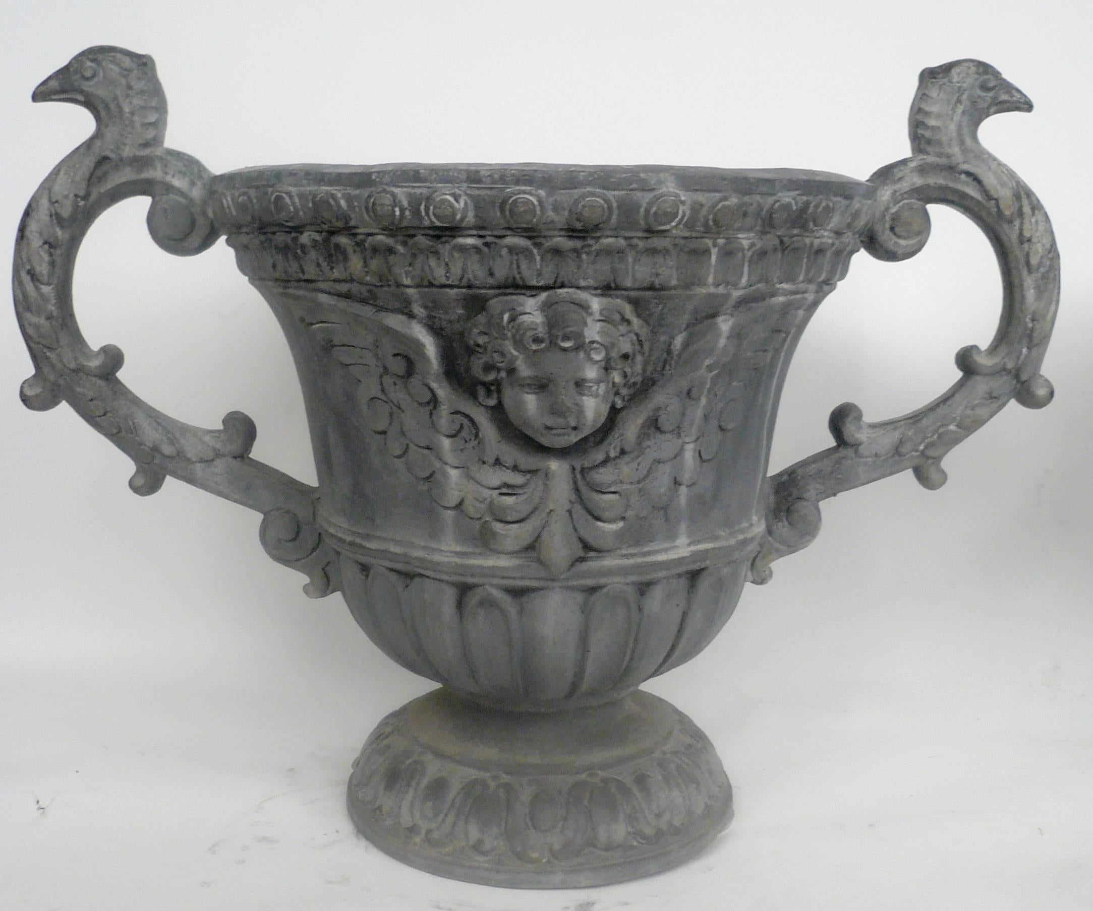 Pair of English Baroque style twin handled lead urns, with winged cupid head motif.