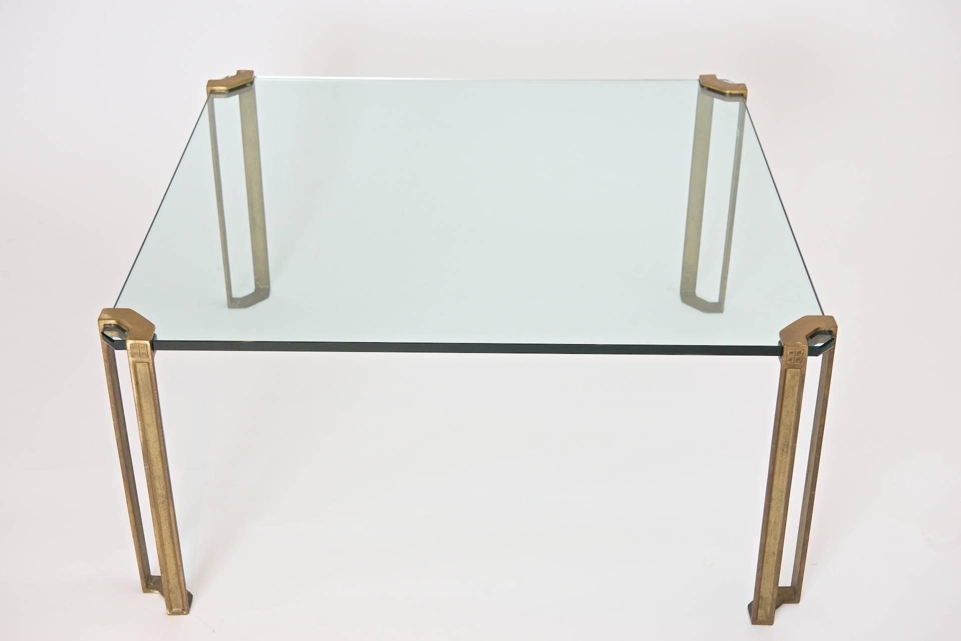 'Frameless' coffee table; glass clamped by four brass 'legs'.

Minimal and innovative table design by Peter Ghyczy.