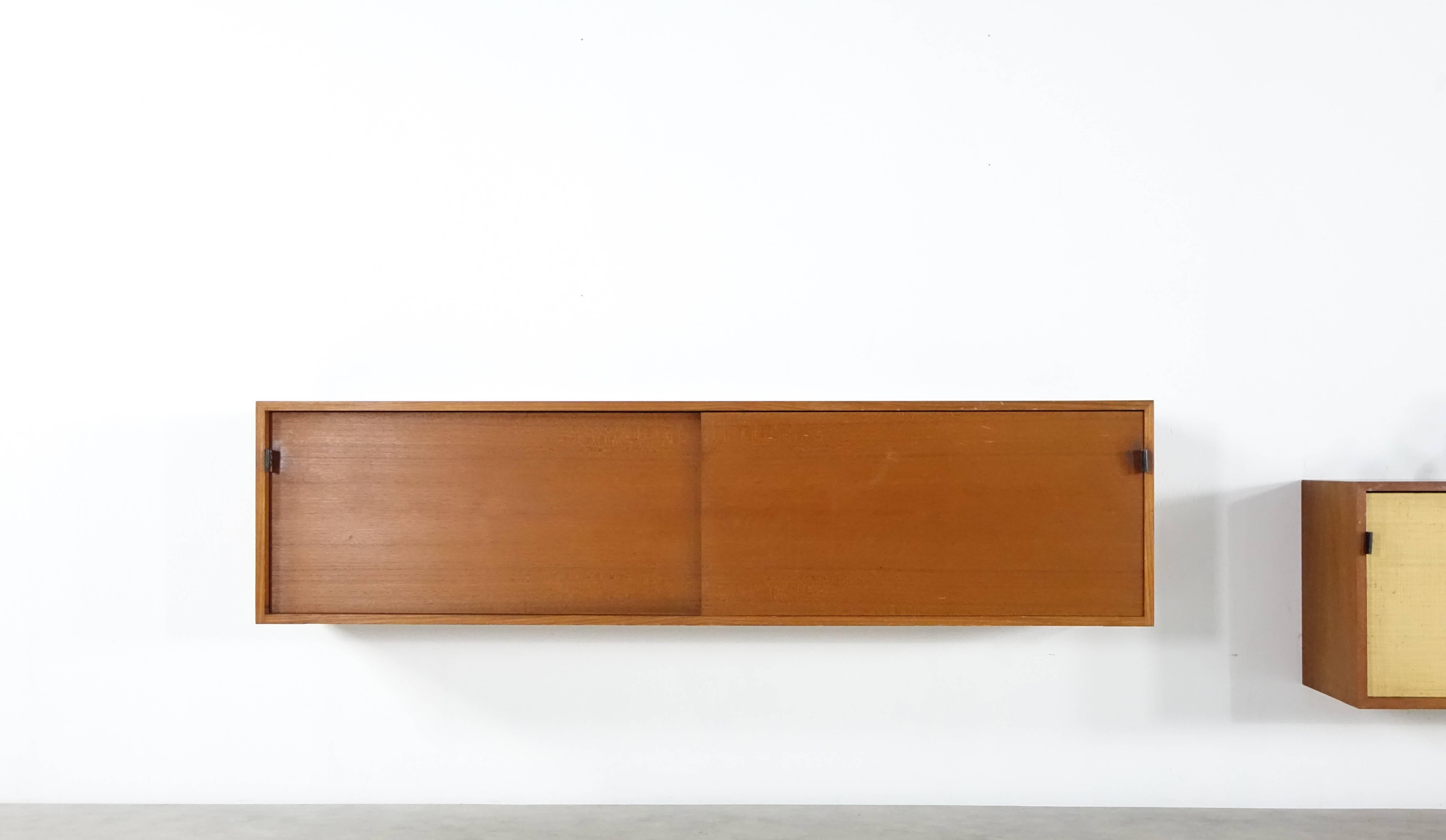 Sideboard mod°123.
By Florence Knoll for Knoll International in 1952.

Sideboard comes in teak, sliding doors mit leather grips. Original labels on the backside. Wall-mounted.

Very nice interior with drawers. Excellent condition!

Dimensions