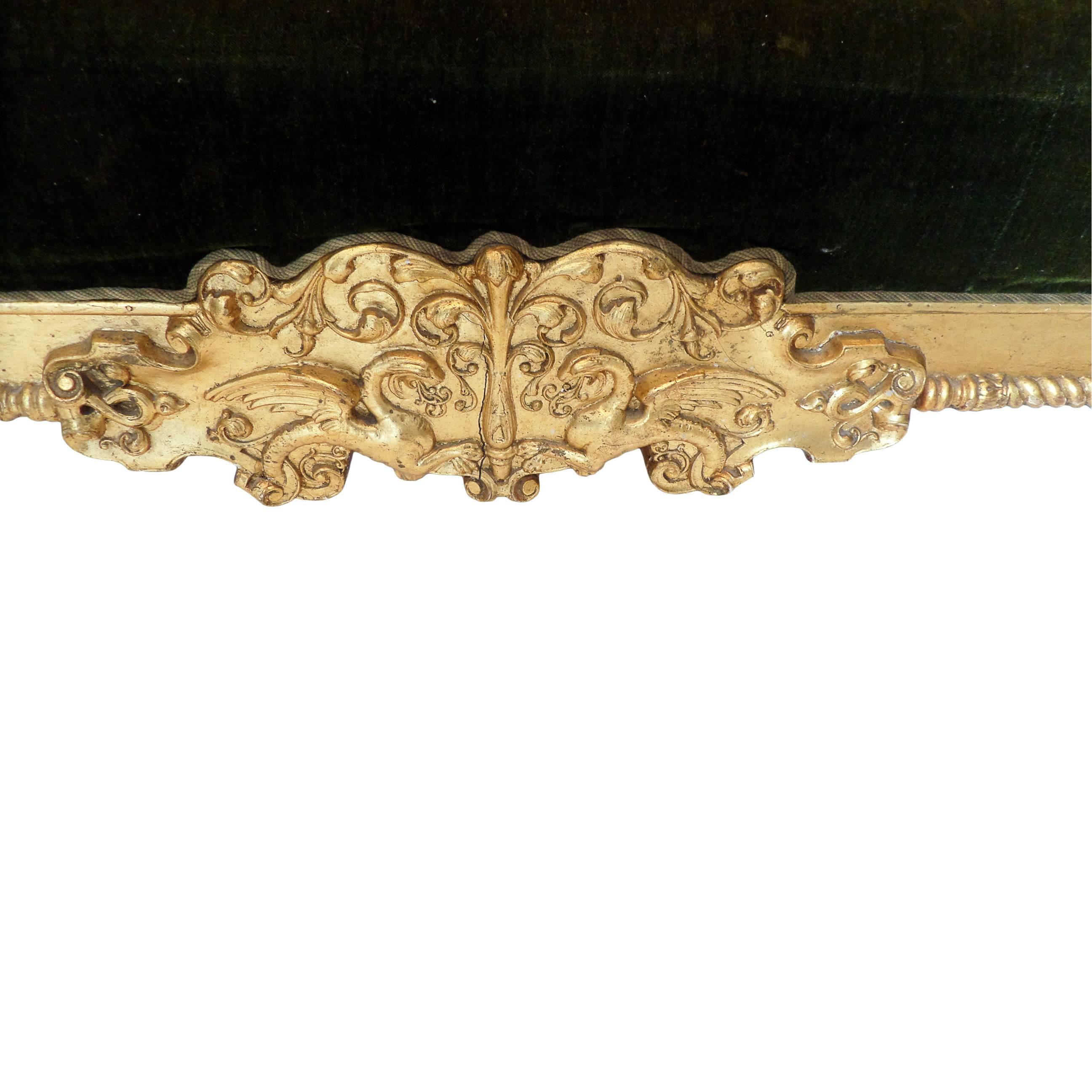 This elaborately carved and gilt sofa is ornamented with mascherones and mythological figures and upholstered with moss-green velvet, the back deep-buttoned. Traces of the original upholstery at the back.