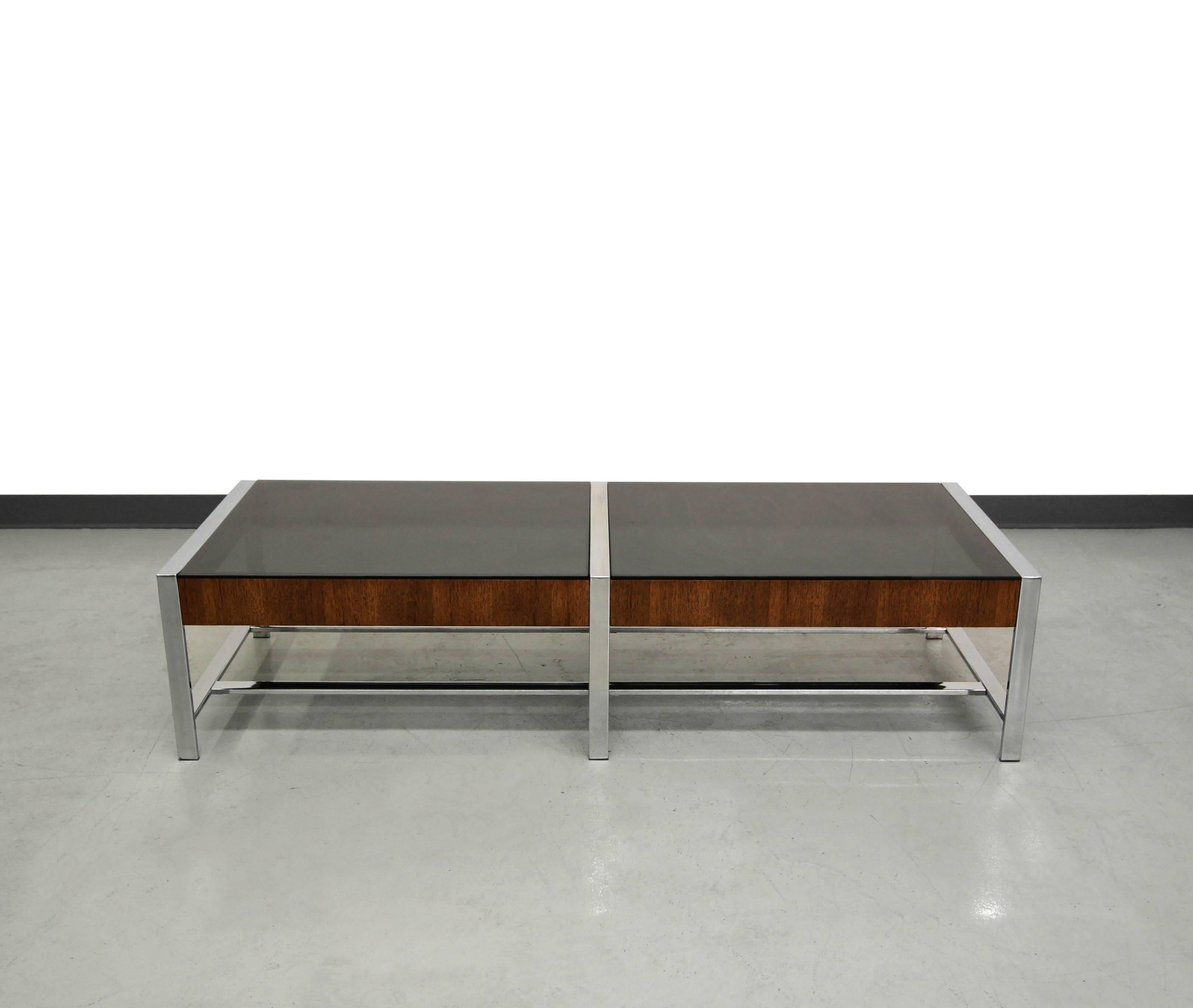 Modern and sleek designed Mid Century coffee table in the manner of Milo Baughman. Table features mirrored chrome framework with walnut details and smoked gray glass. Would look great meshed with modern or Mid-Century decor.