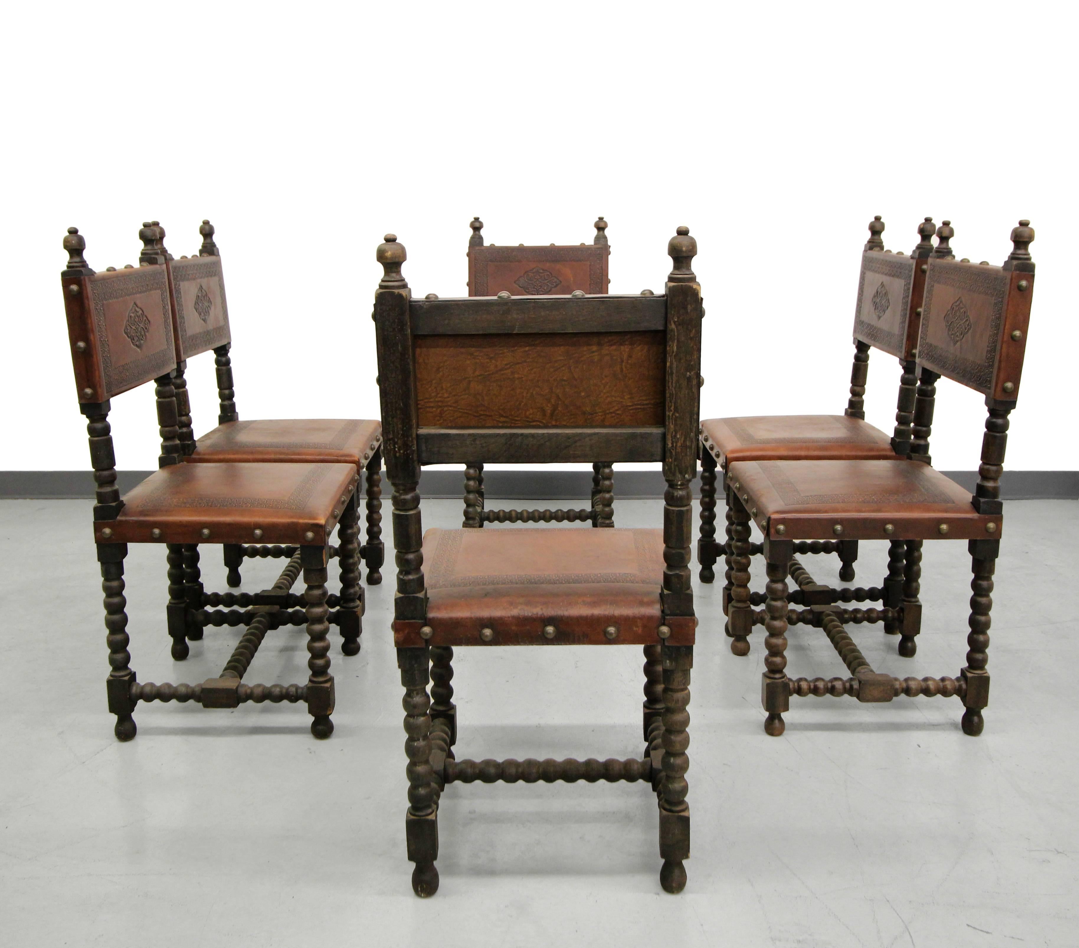Gorgeous set of six early 20th century, antique Spanish Colonial dining chairs. These chairs feature beautiful stamped leather and hand-turned wood details with large brass tack details. Would be perfect in an eclectic or Industrial decor.

These