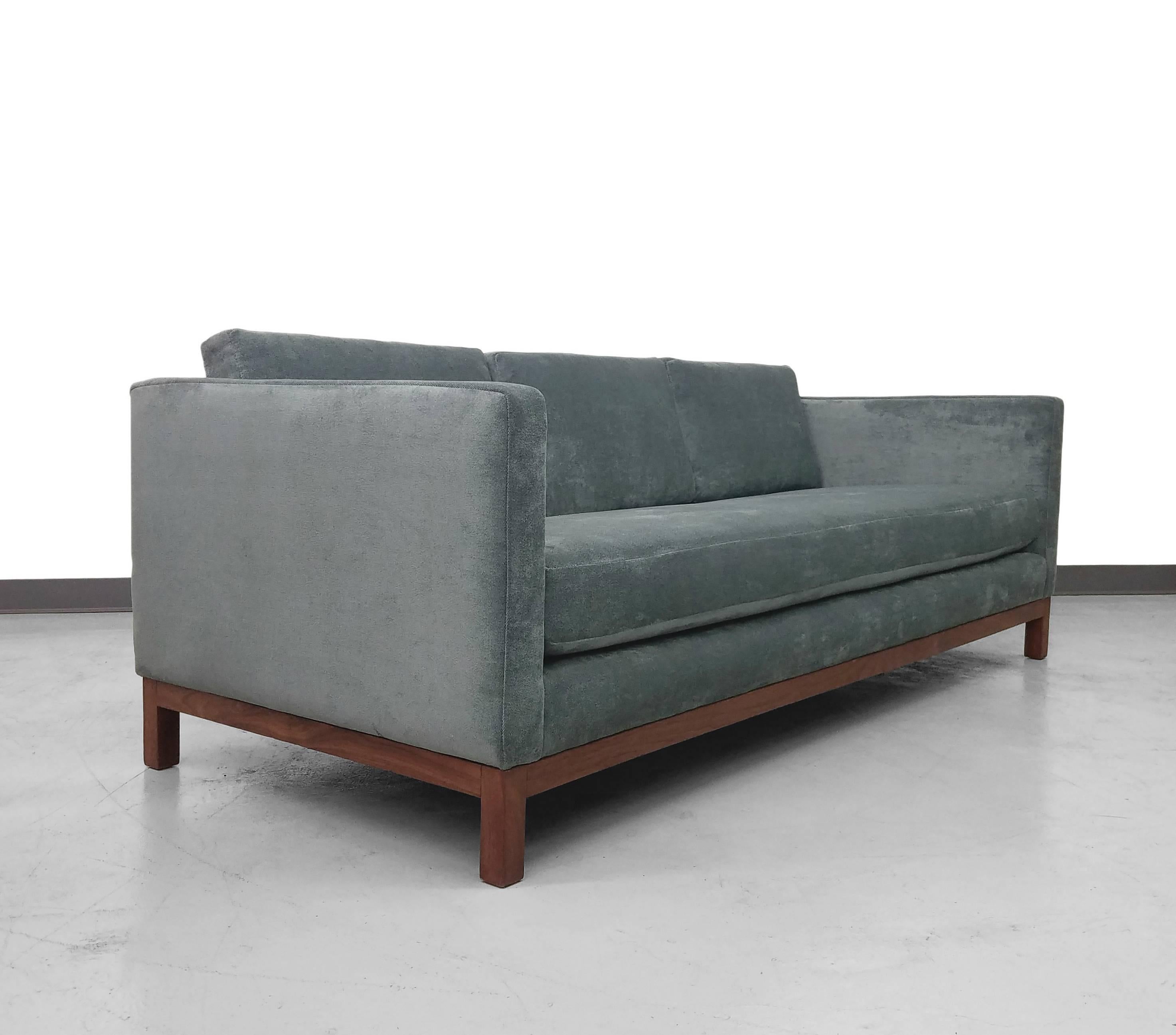 Beautiful Mid-Century tuxedo style sofa by Milo Baughman. Sofa floats on a beautiful walnut base that gorgeously contrasts the deep blue green fabric. Simple, classic lines and details make this the perfectly understated statement piece. Newly