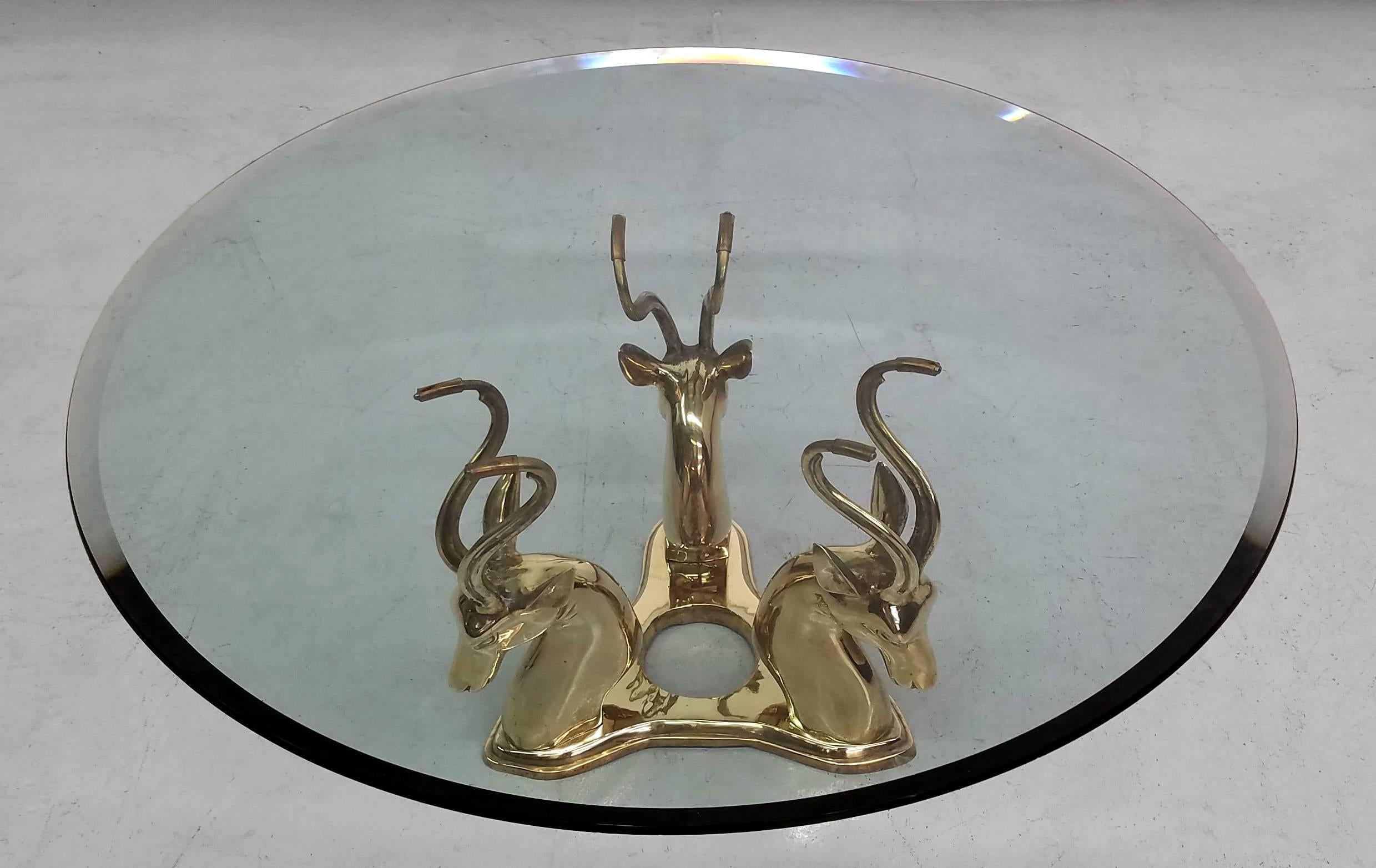 This is a beautiful Hollywood Regency style solid brass antelope coffee table. Base is an antelope trio constructed of solid brass. Very substantial statement piece.

Base measures: 18