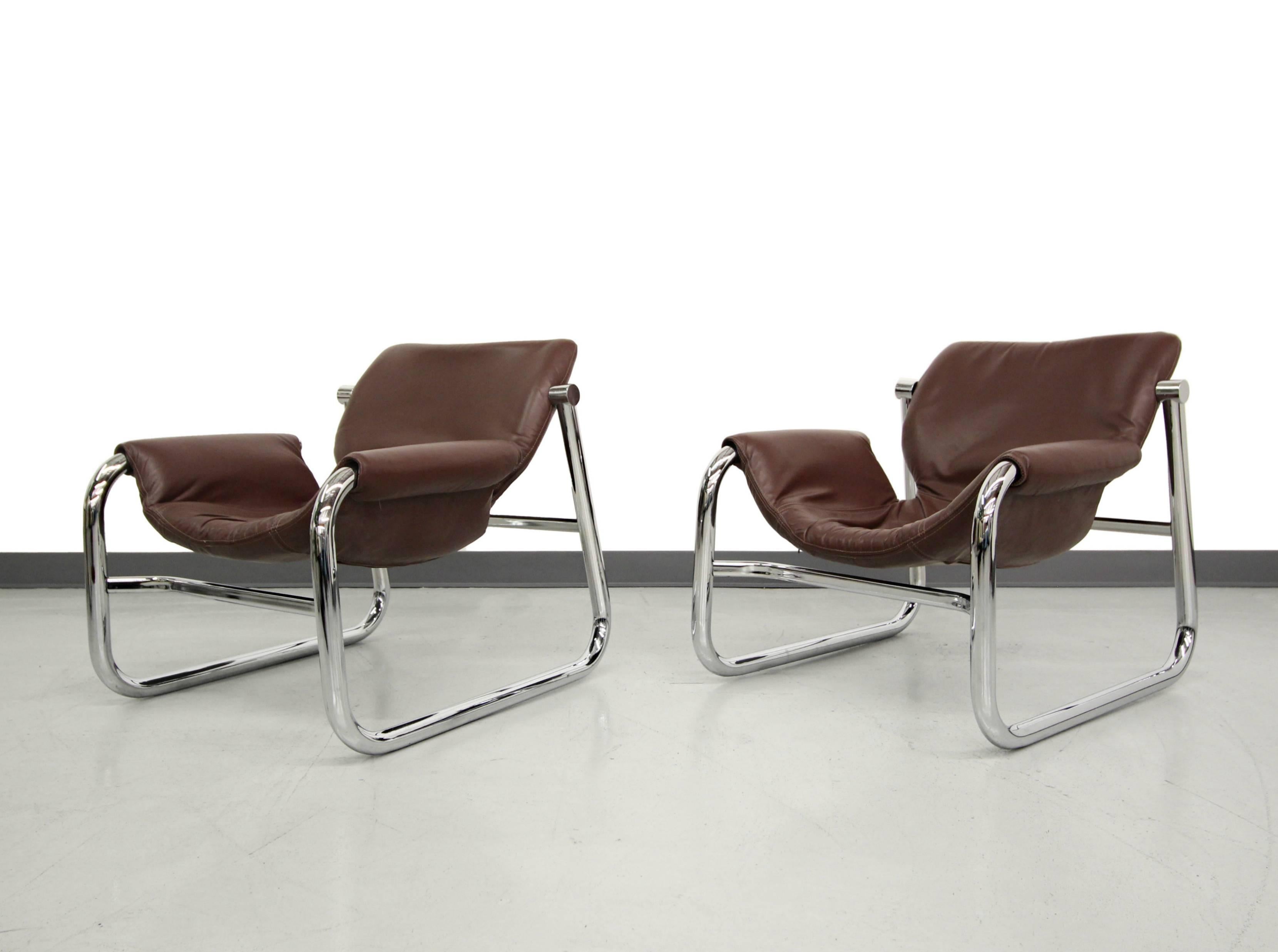 Pair of chrome and leather Alpha lounge chairs by Maurice Burke, for Pozza Brazil. Chairs are comprised of a maroon leather sling on a mirrored chrome frame. Relaxed profile and stylish.