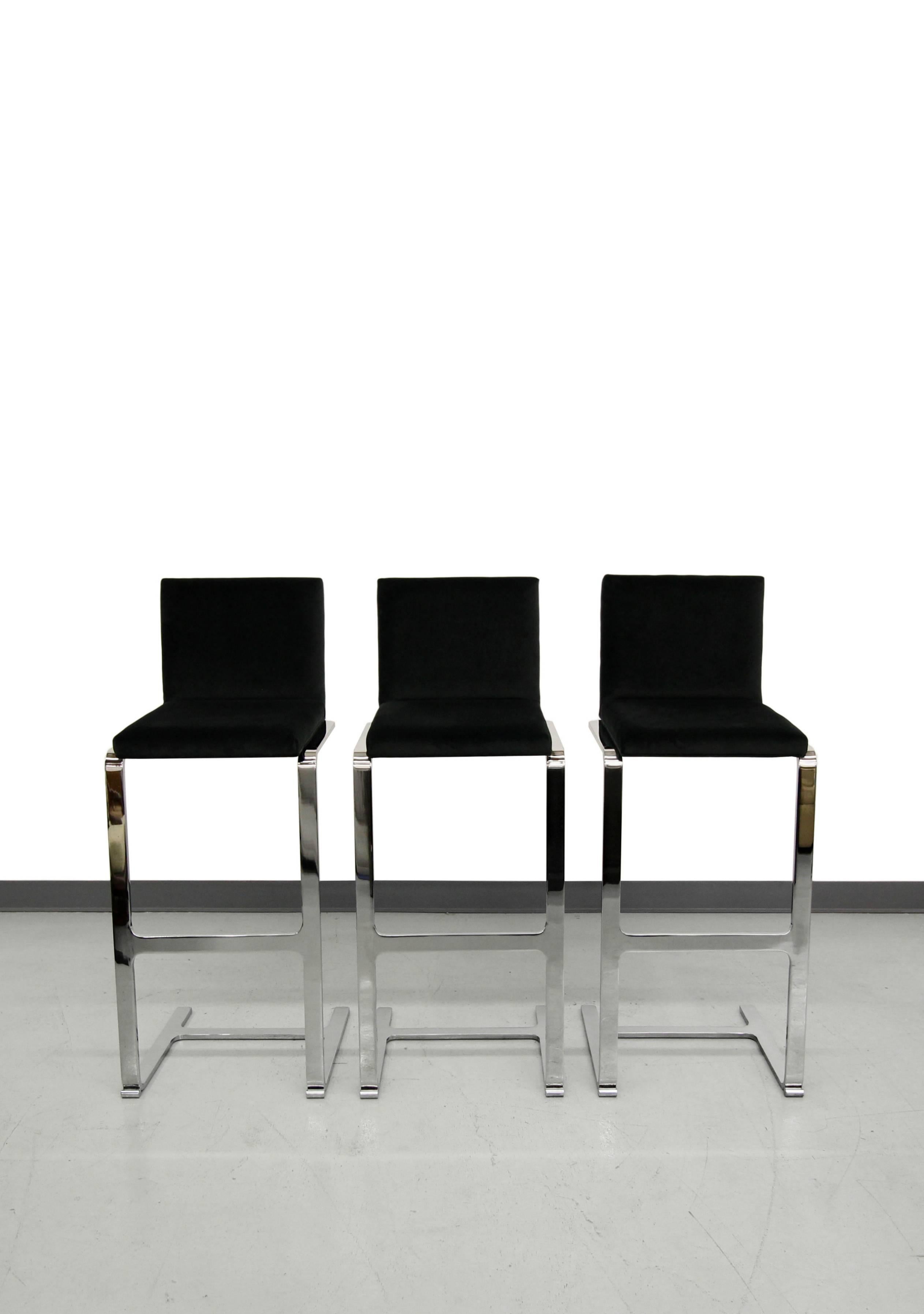 Set of three chrome, counter height, cantilever bar stools in the style of the Brno line designed by Mies van der Rohe for Knoll. Stools are heavy duty with beautiful mirrored, flat bar chrome frames and all new black velvet upholstery. They are in